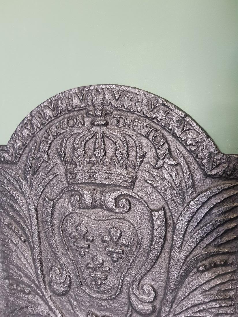 18th century French cast iron hob with the family crest of the House Bourbon with an unclear text, the weapon consists of a crown with 3 fleurs-de-lys (lilies, symbol royal house), flanked by palm branches (victory) on either side. It's in a good
