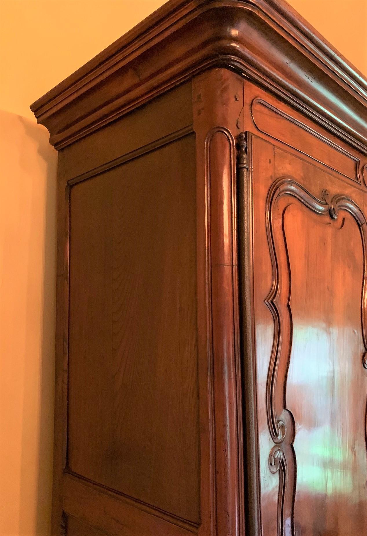 Fabulous 18th century French cherrywood armoire with clean lines and a beautiful warm patina. The four cupboard doors with finely carved and shaped inset panels, and mounted with iron and brass hardware. The entire on a contoured skirt and short