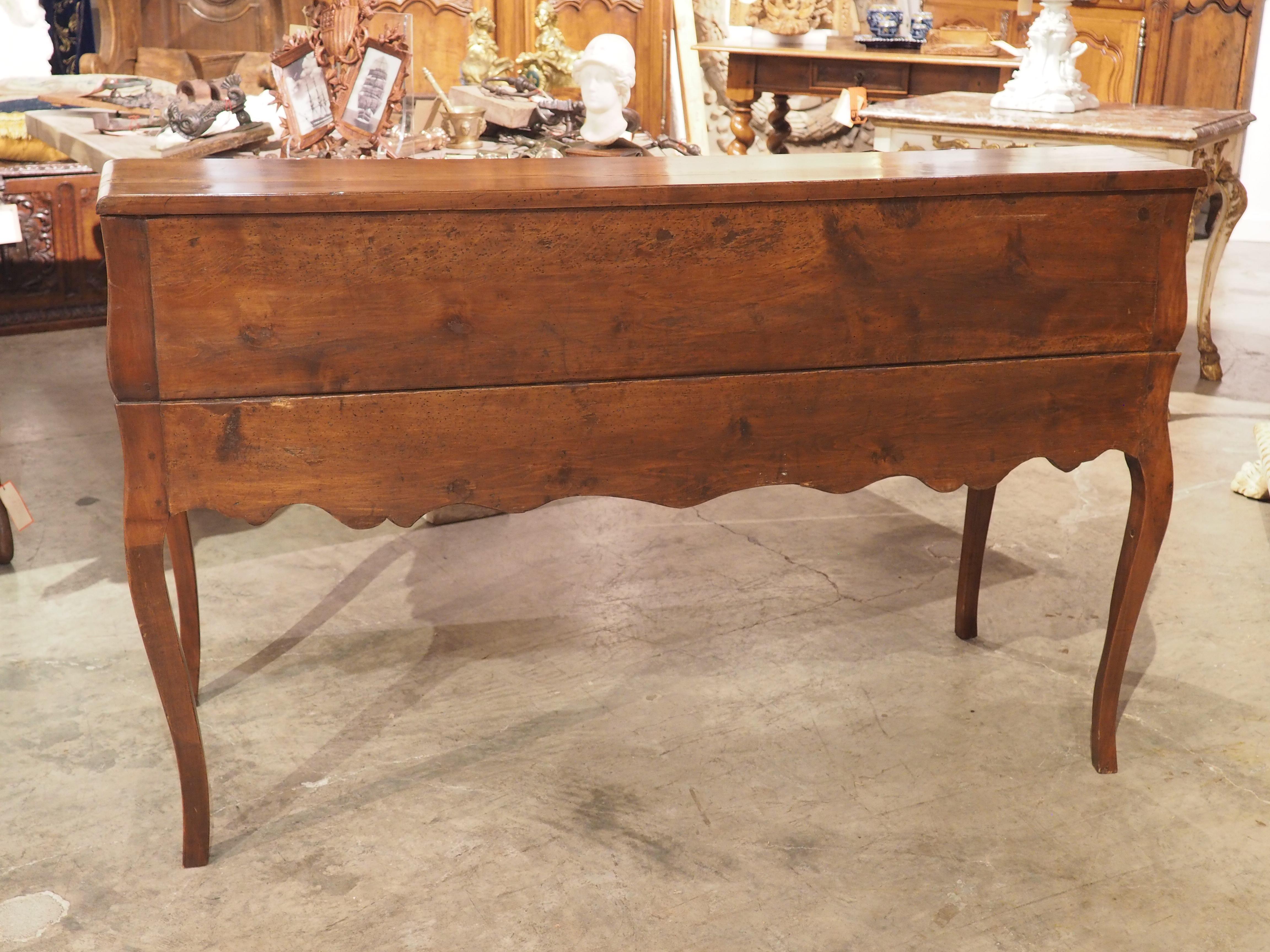 Larger than the typical Louis XV writing desk, this cherrywood bureau de pente was hand-carved in France during the late 1700’s, just after the period ended. This type of desk went by several names, including bureau dos d’âne and secrétaire à dessus