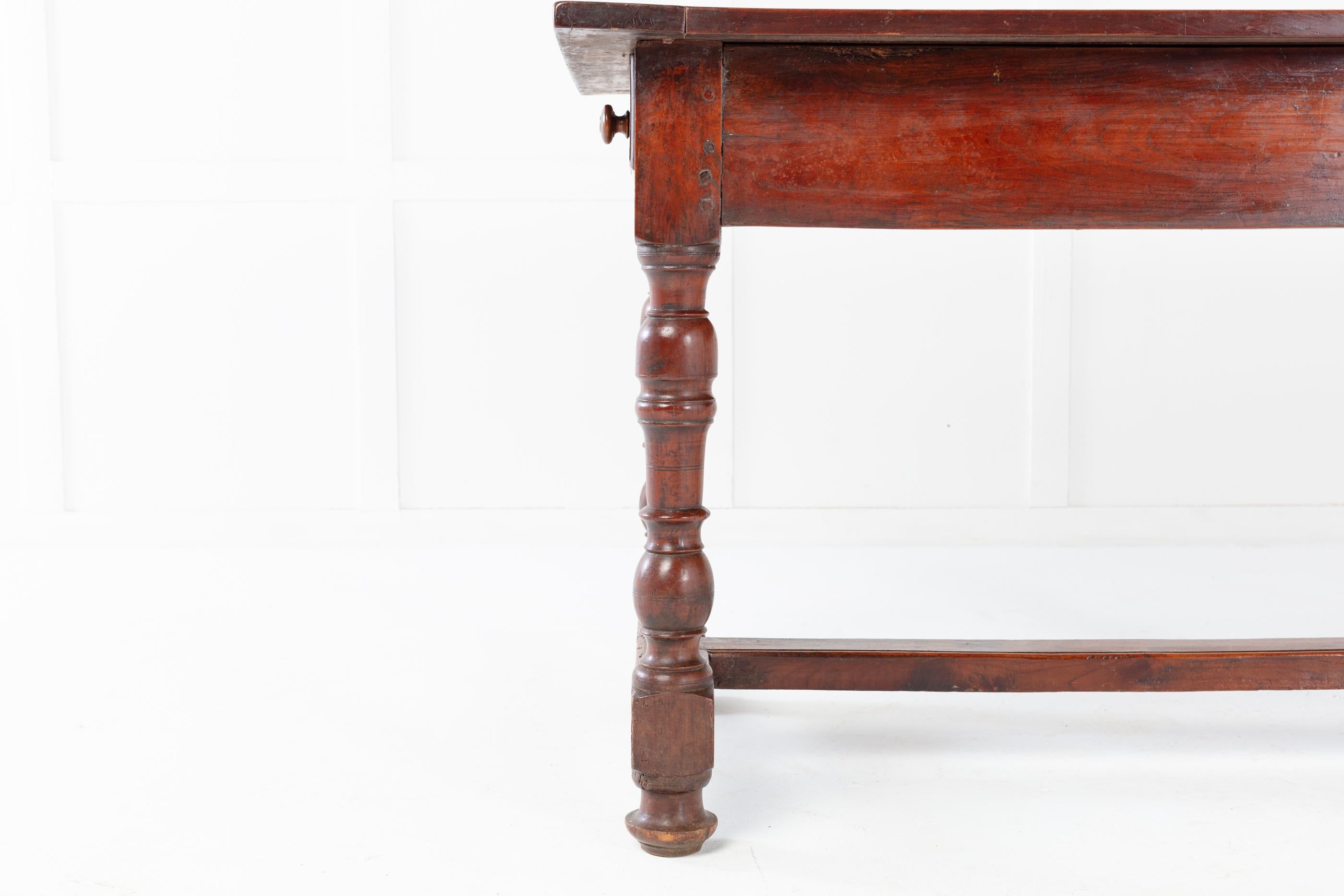 Französischer Esstisch aus Kirschholz des 18. Jahrhunderts mit zwei Schubladen, eine an jedem Ende, auf gedrechselten Beinen. Die mittlere Bahre und das mittlere Bein wurden aufgrund von Alter und Gebrauch irgendwann ersetzt.

Dieser Tisch hat