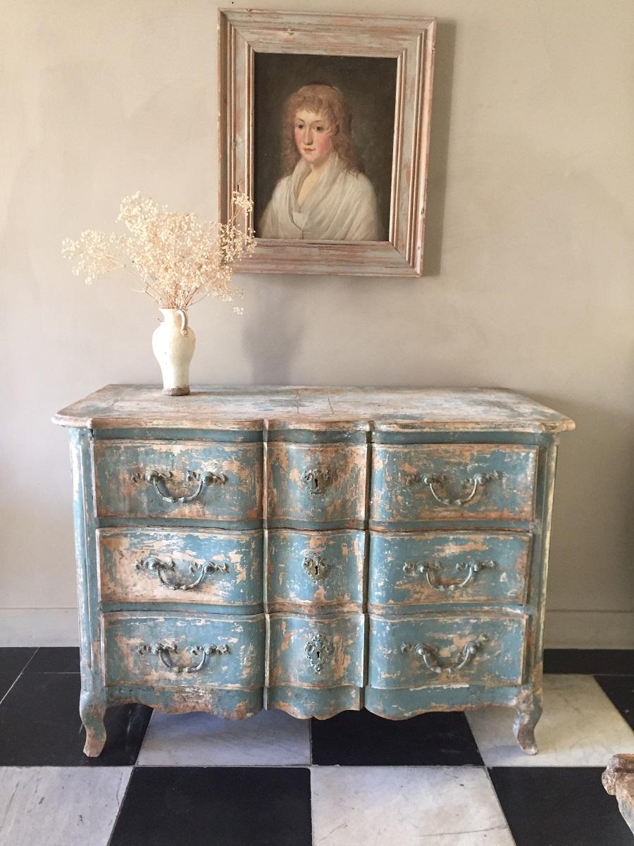 A Louis XV period commode bombé with original paint remains. This chest of drawers is beautifully sculpted out of well grained chestnut. Additionally to the curved lines it has a inlaid top with parquetry work. The patina of the paint is a work of