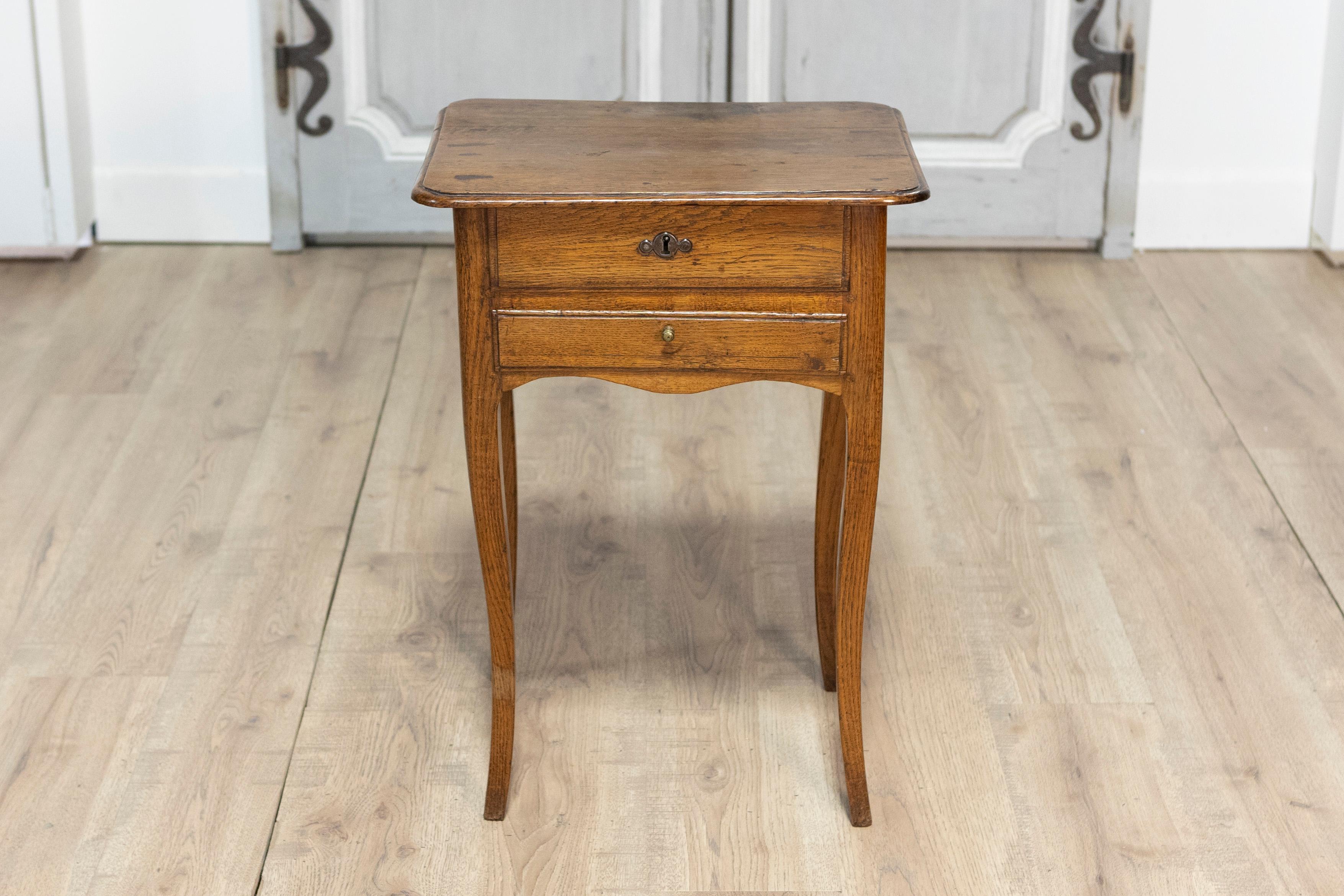 This charming 18th-century French chevet table is a timeless example of Louis XV style, blending functional design with graceful aesthetics. Crafted from oak wood, the table showcases a warm, rich patina that highlights the natural grain and age of
