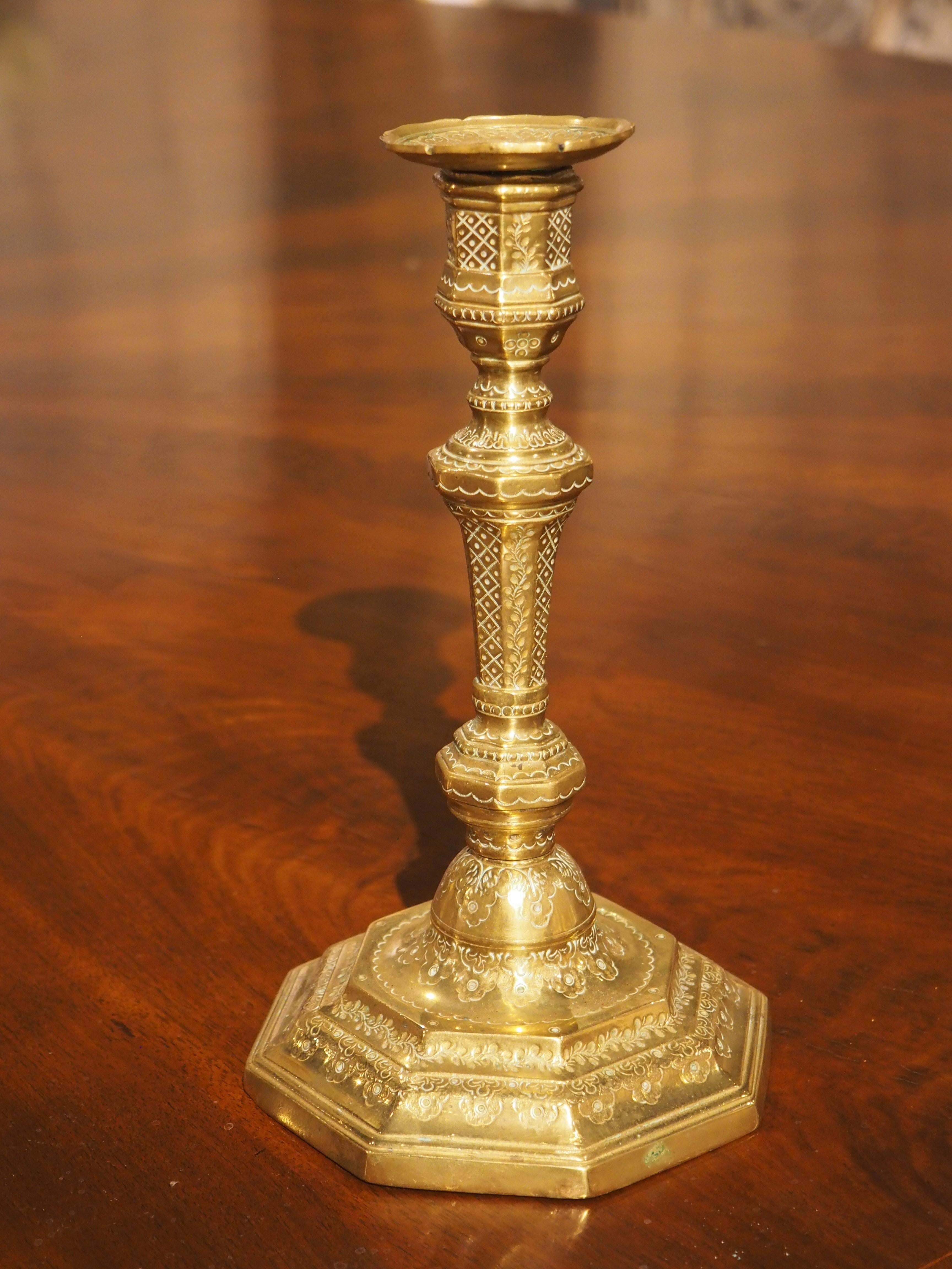 This lovely, gilded bronze candlestick was hand-chiseled in France in the 1700’s. An undulating column rises from the center of an octagonal base that has been engraved with floral and foliate motifs along all three levels of the stepped molding.