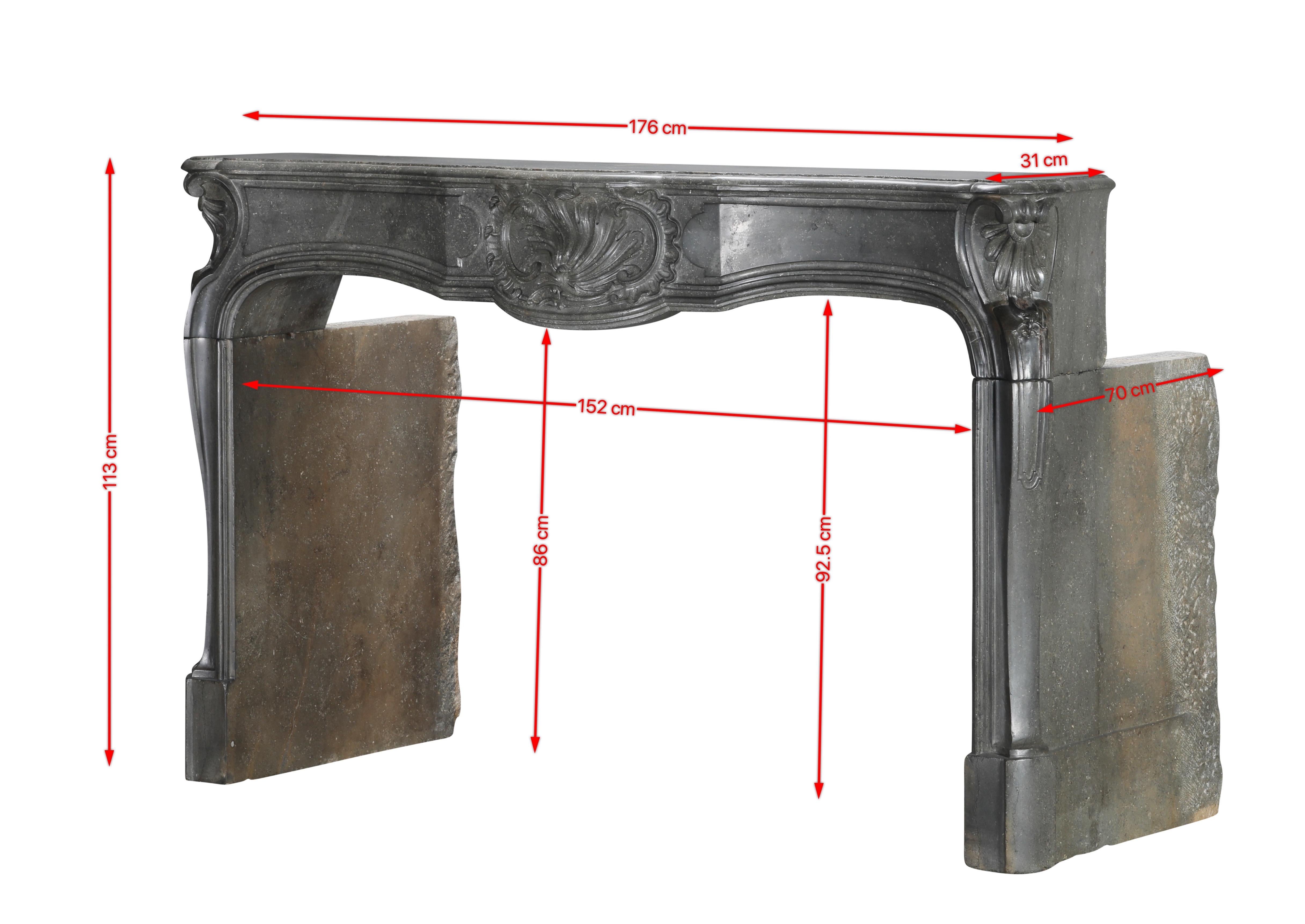 Gorgeous 18th century period mantelpiece in French stone with a polished finish.
It features intricate carvings, including shell scroll motifs, especially in the central panel and upper corners. The jambs are curved and have also decorative