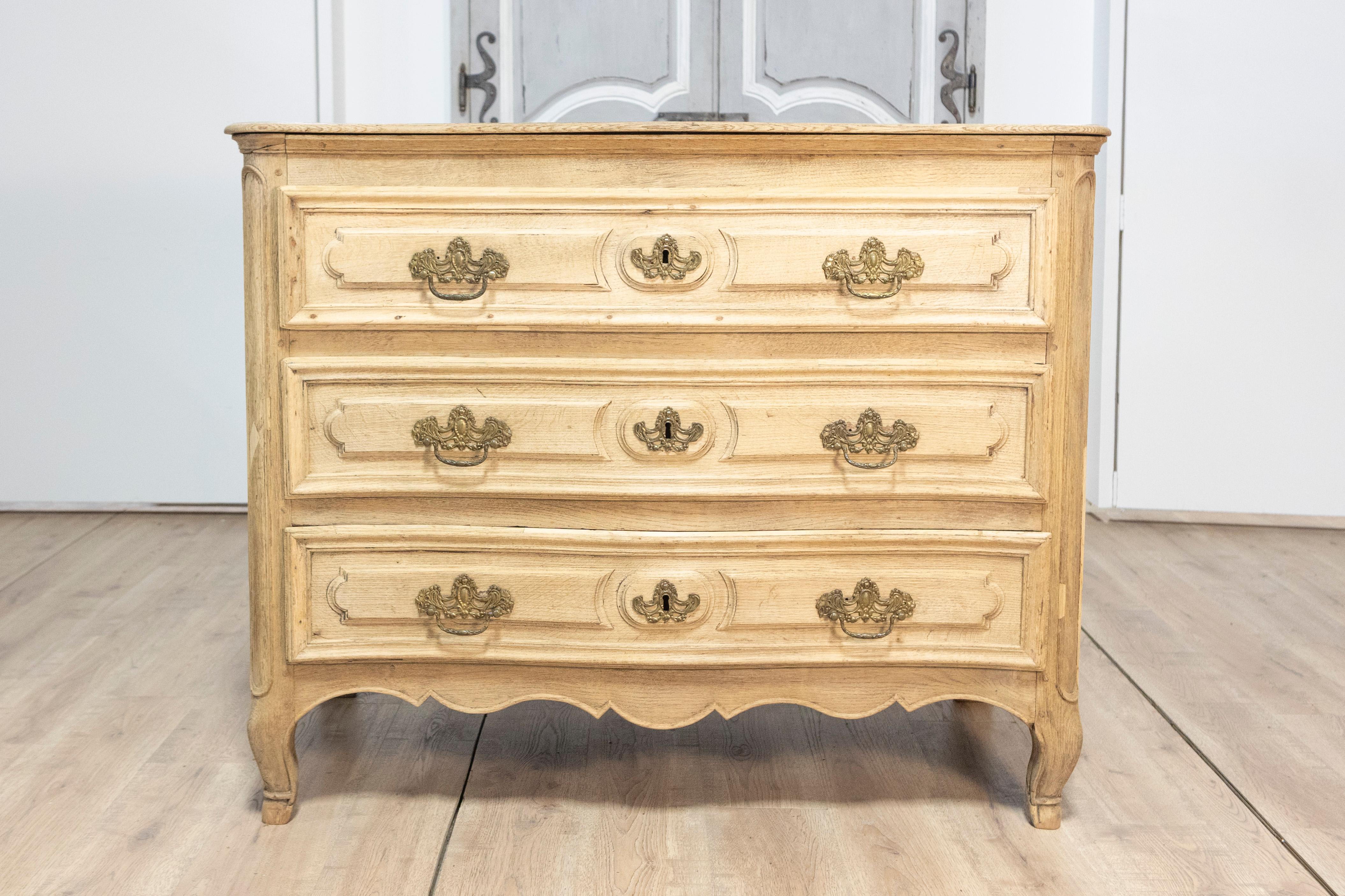 Questa squisita commode francese del XVIII secolo incarna l'eleganza e la maestria senza tempo del periodo Luigi XV. Realizzata in rovere massiccio, la commode presenta un frontale graziosamente curvo con tre cassetti impreziositi da maniglie ed