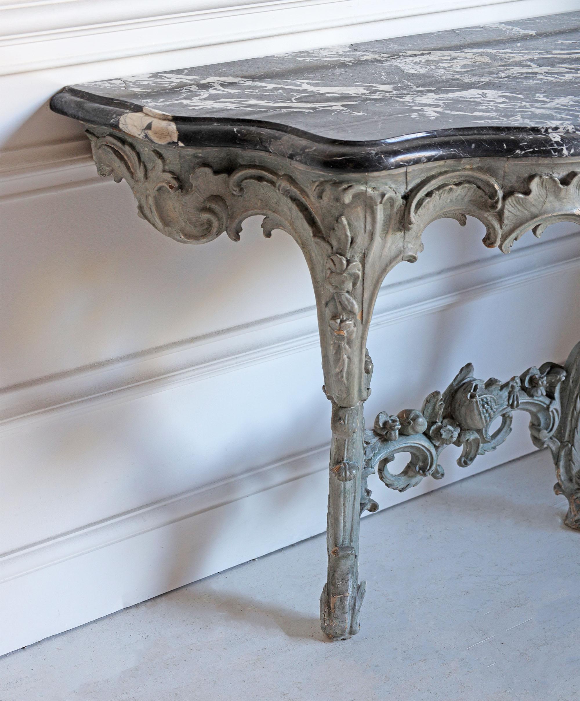 French console with black marble top from circa 18th Century.
A Louis XV console table with well carved decoration of roccoco scrolls, garlands of flowers and leaves. 

