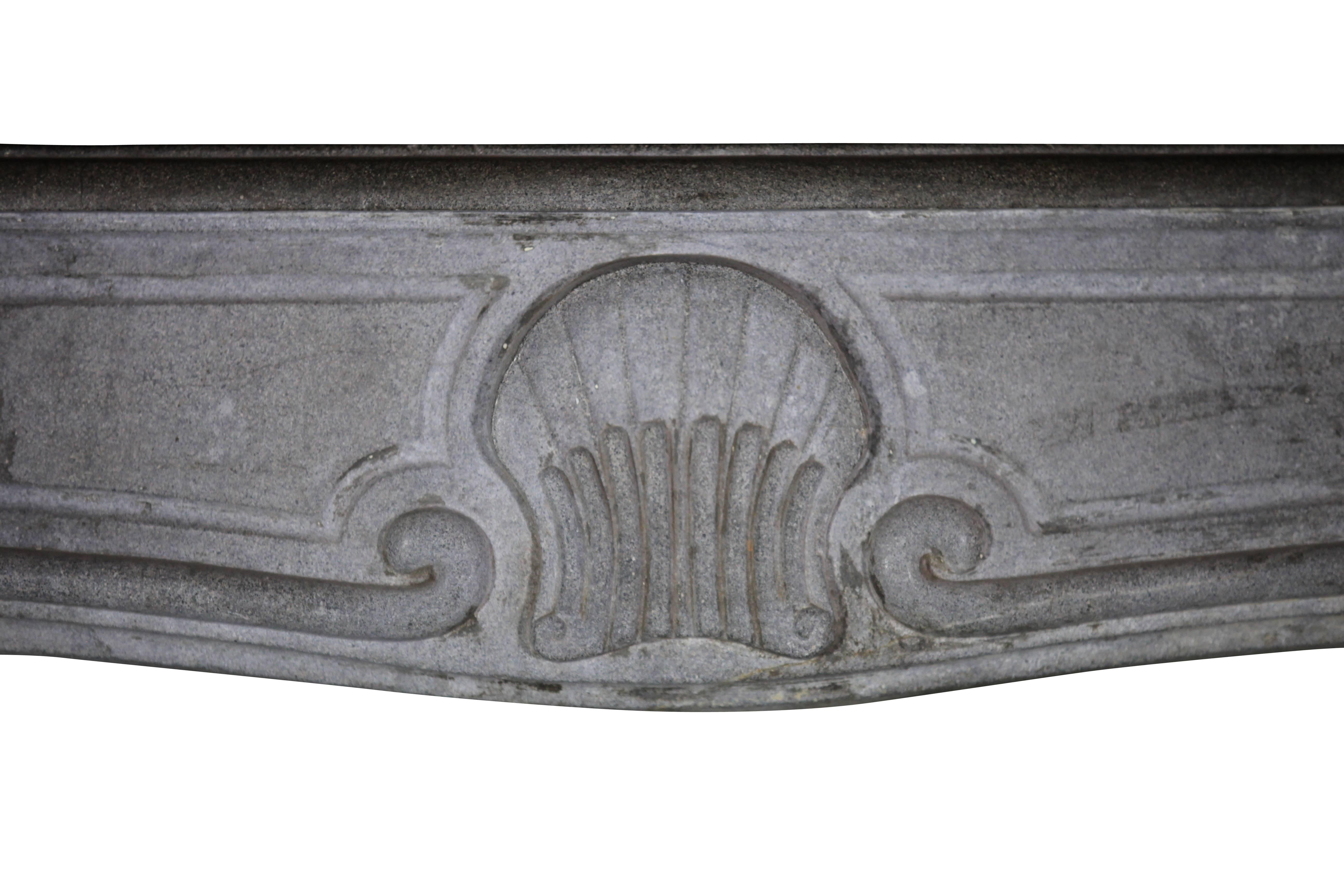 A bicolor bleu-grey French Burgundy hard limestone fireplace surround with little remaining of patin and a rustic twist. It has a lovely shell shaped carving on the front typing the Regency to Louis XV period. 
Measures:
153 cm EW 60,24