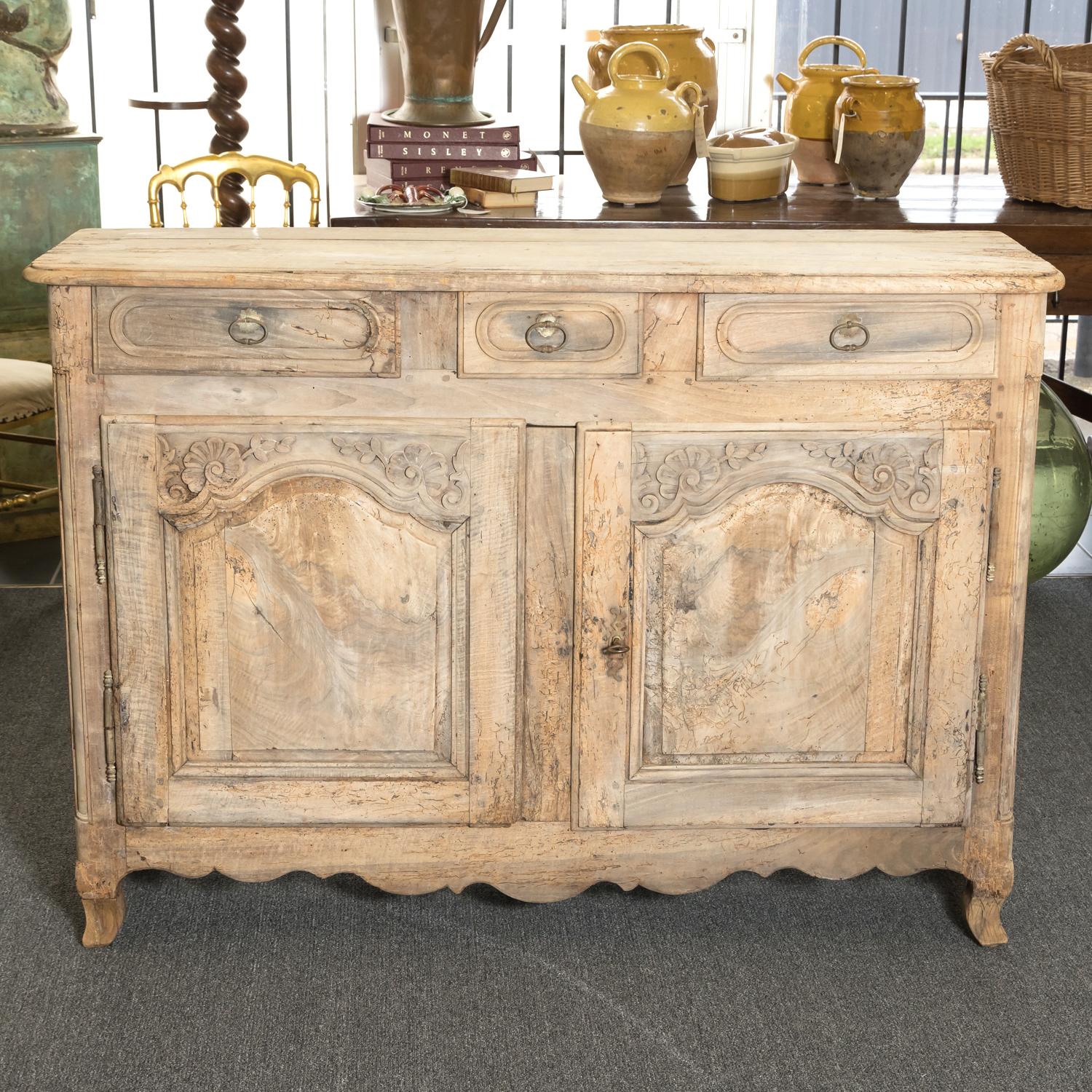 An 18th century French Country Louis XV period carved buffet handcrafted of solid walnut that's been bleached or washed to a natural finish by talented artisans in the Normandy region, circa 1760s. This charming washed oak buffet, with it's crusty,