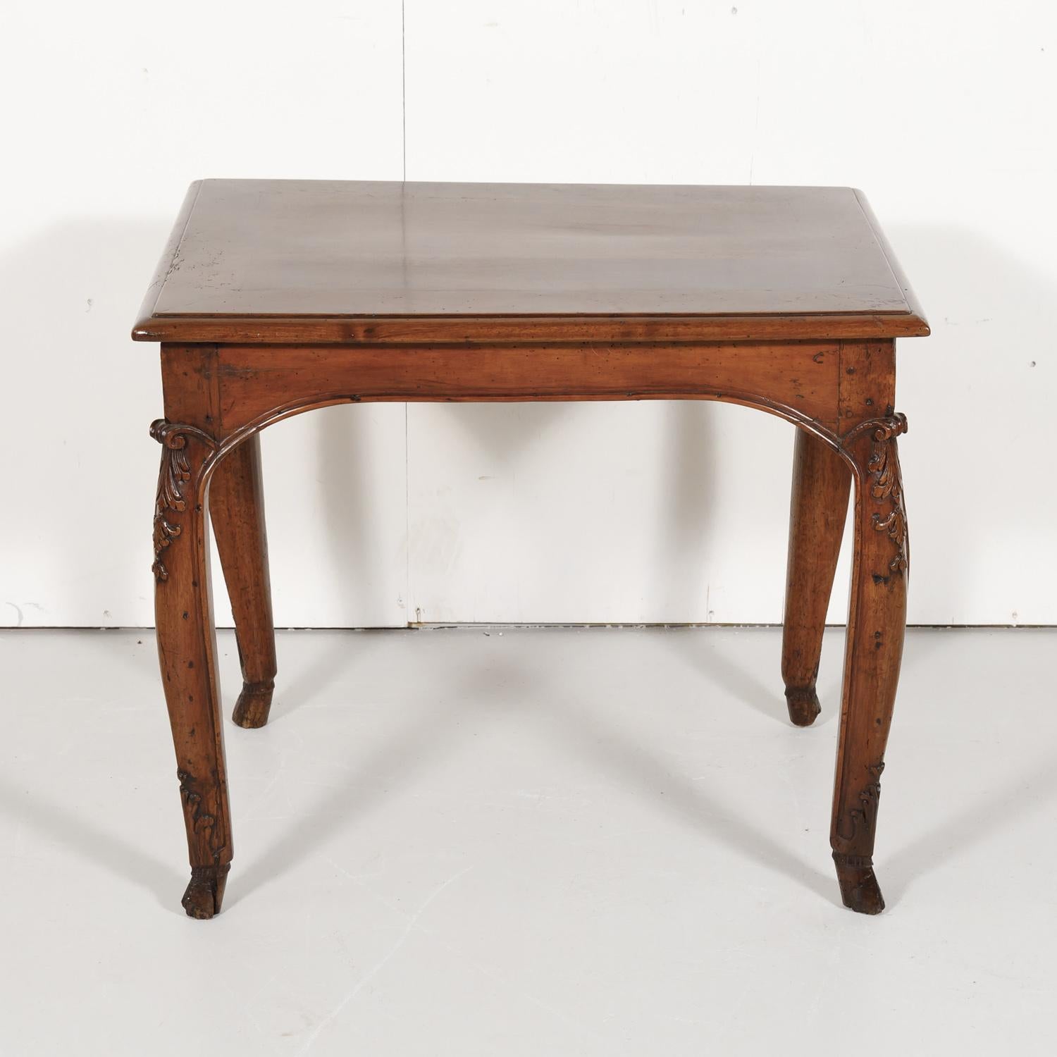 Lovely 18th century French country Louis XV period side table handcrafted of solid walnut in Lyon, circa 1740s, having a moulded top above a curved frieze. Raised on gently curving cabriole legs that have beautifully carved acanthus leaves at the