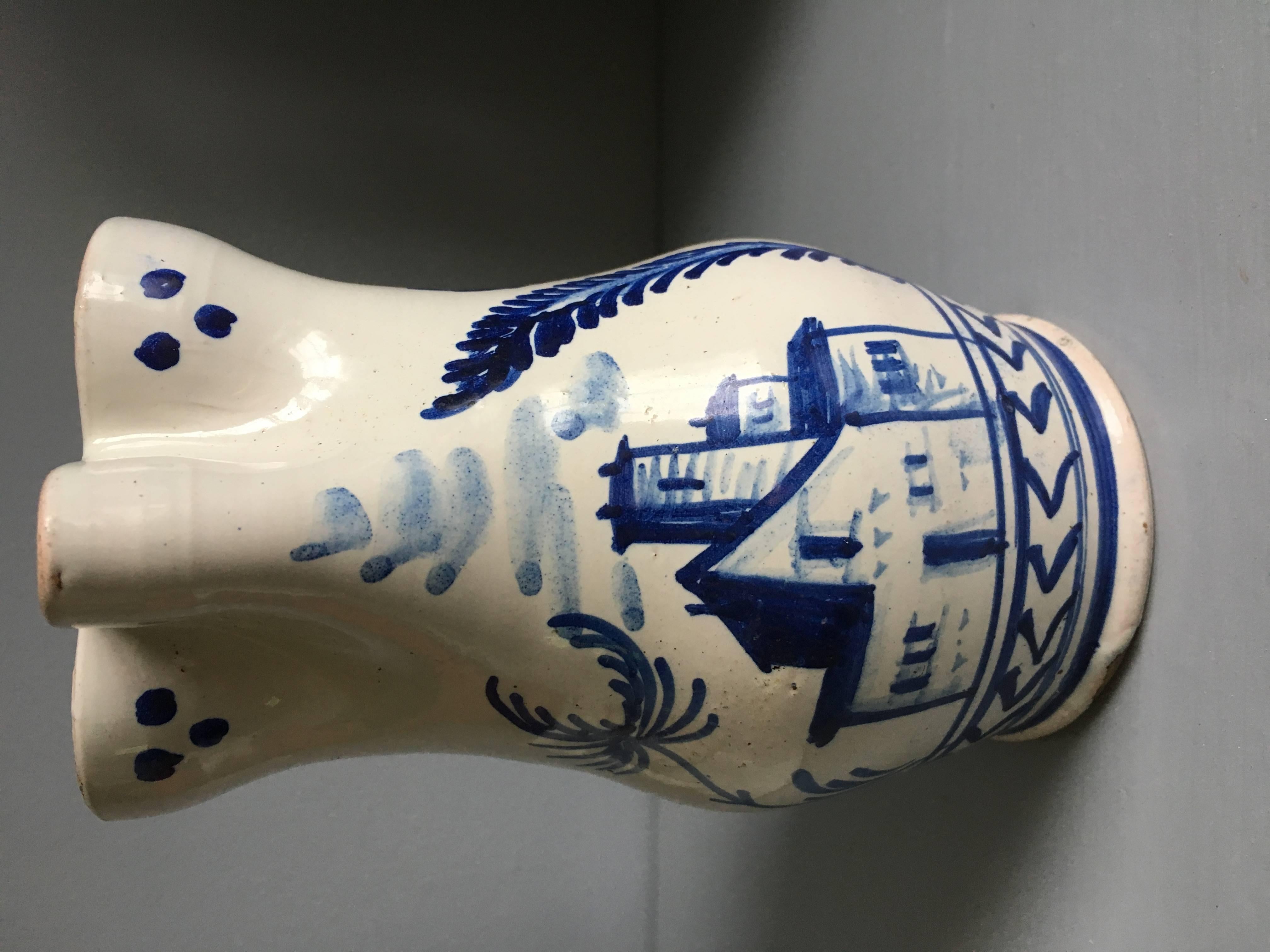 A charming 18th century blue and white cream pitcher decorated with a manor house and trees. From Nevers, France.