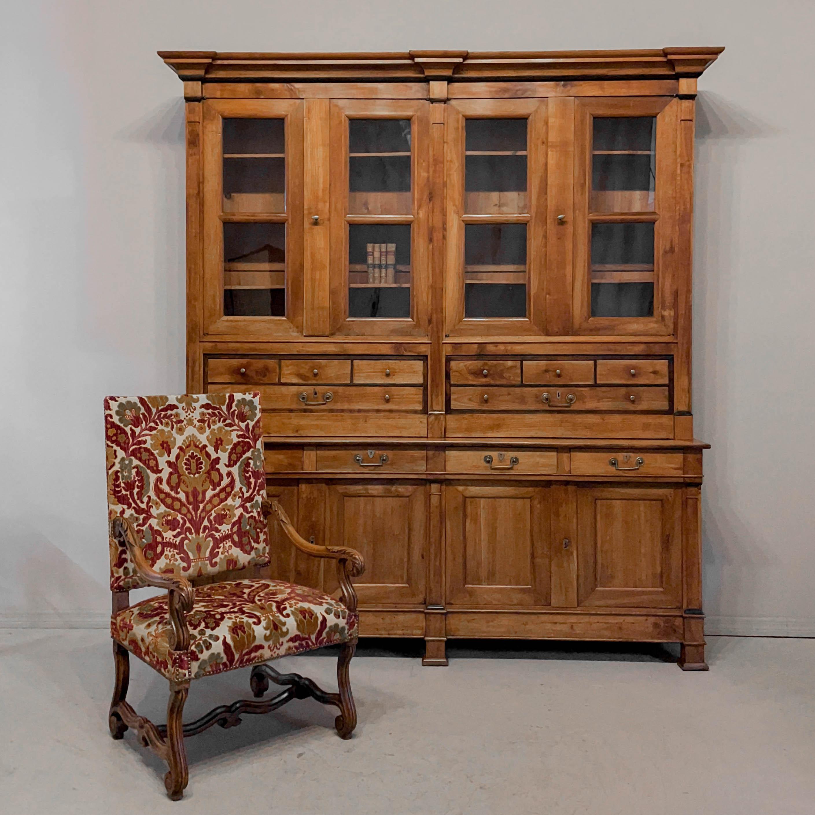 A late 18th Century French Directoire Period buffet à deux corps or bibliotheque made of solid walnut and cherry wood with pine inlay outlining the glass panes. Pine as a secondary wood. This large cabinet has two parts: the upper case has  two sets