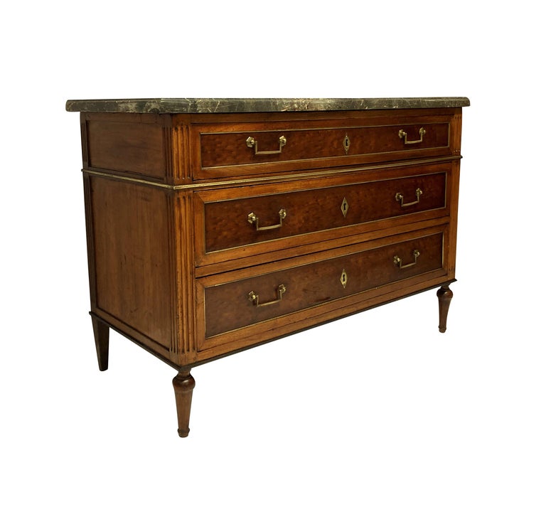 A French XVIII century Directoire commode in light mahogany with three oak lined drawers. With brass detailing and handles and a good, hand cut variegated grey marble top.