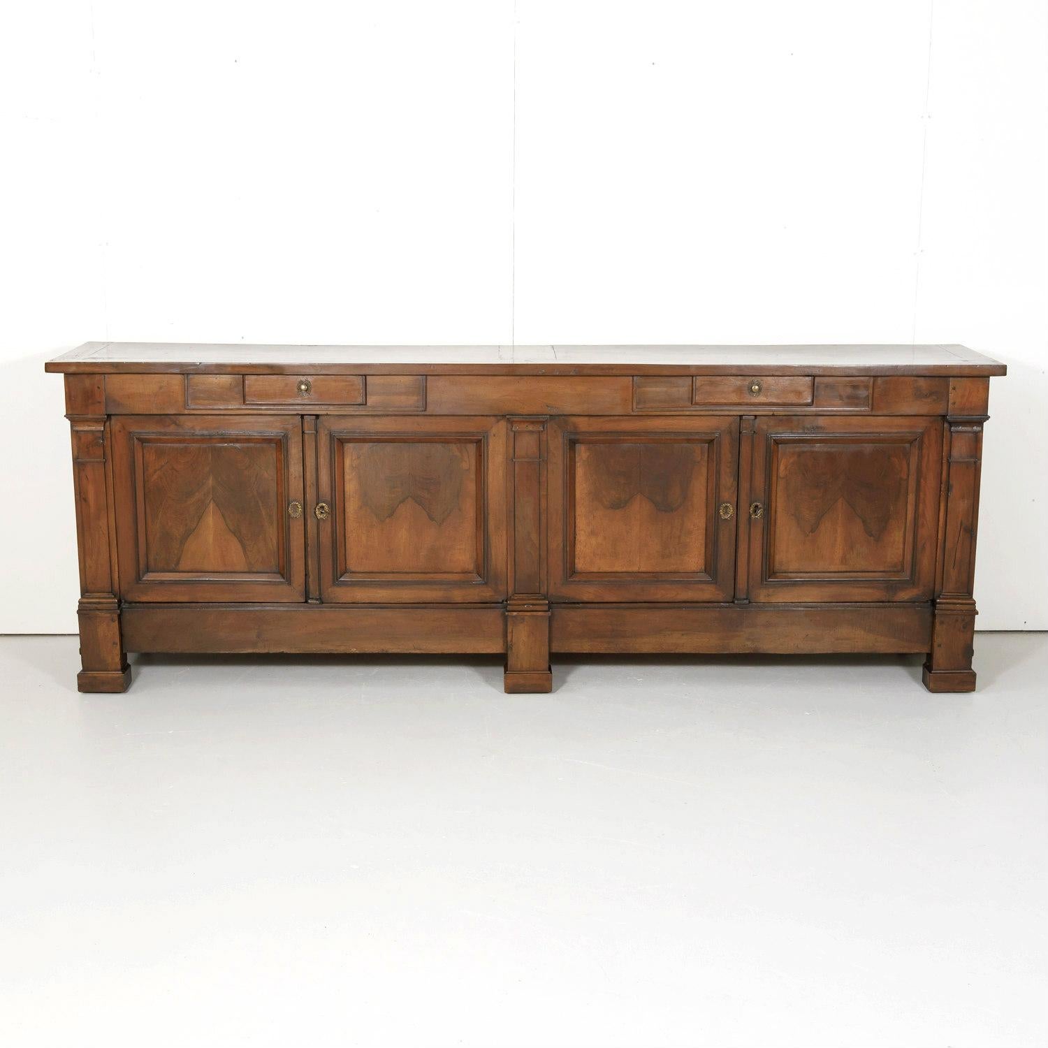 Stunning 18th century French Directoire period enfilade handcrafted of solid walnut by talented artisans in Lyon, circa 1790s. Having a rectangular top above two drawers over four panel doors divided by pilasters. Doors open to reveal a spacious