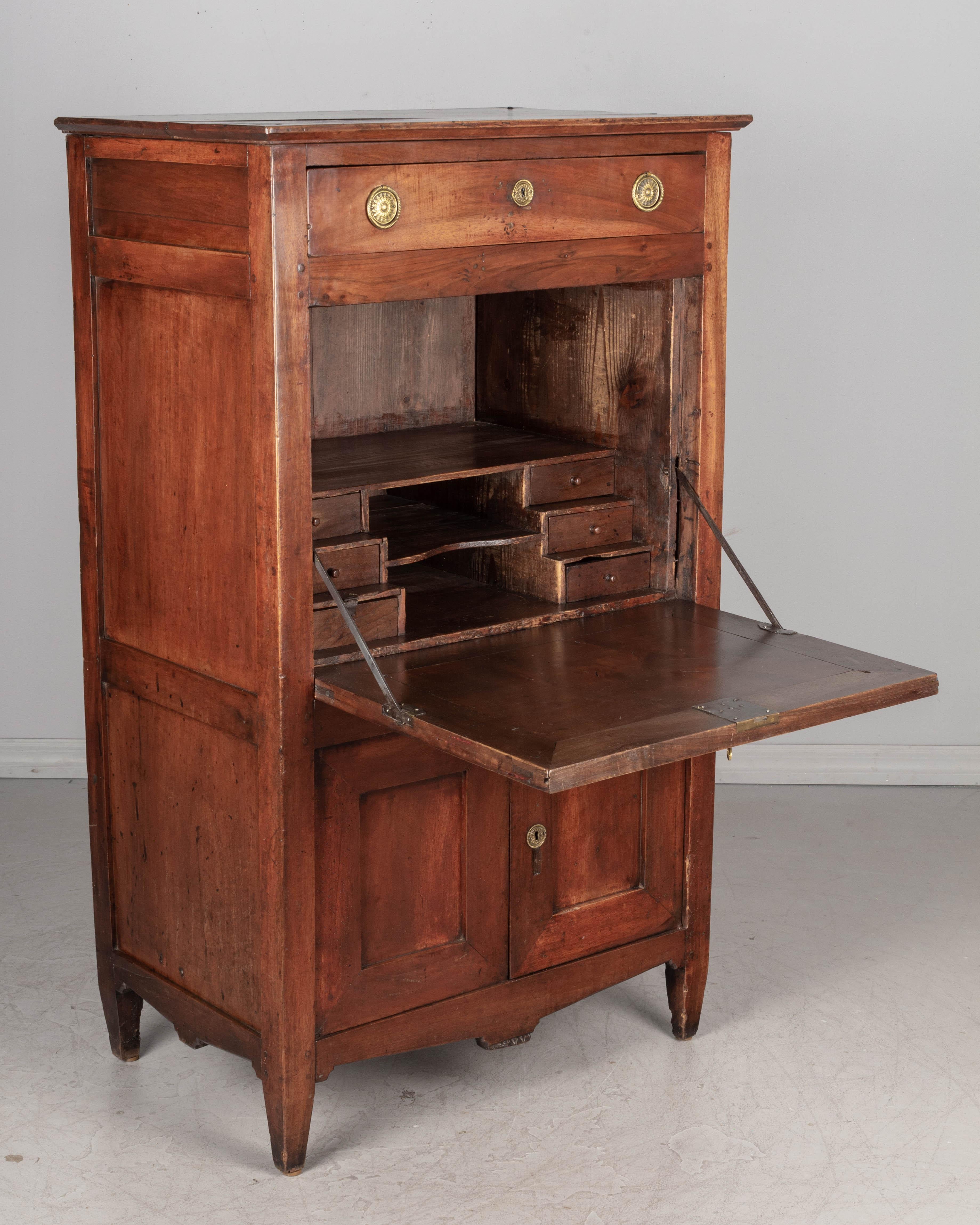 A late 18th century Country French Directoire Period secretaire à abbattant. This drop leaf desk is made of solid walnut, and opens to a pine interior with six small dovetailed drawers. The cabinet below has one interior shelf. One dovetailed drawer