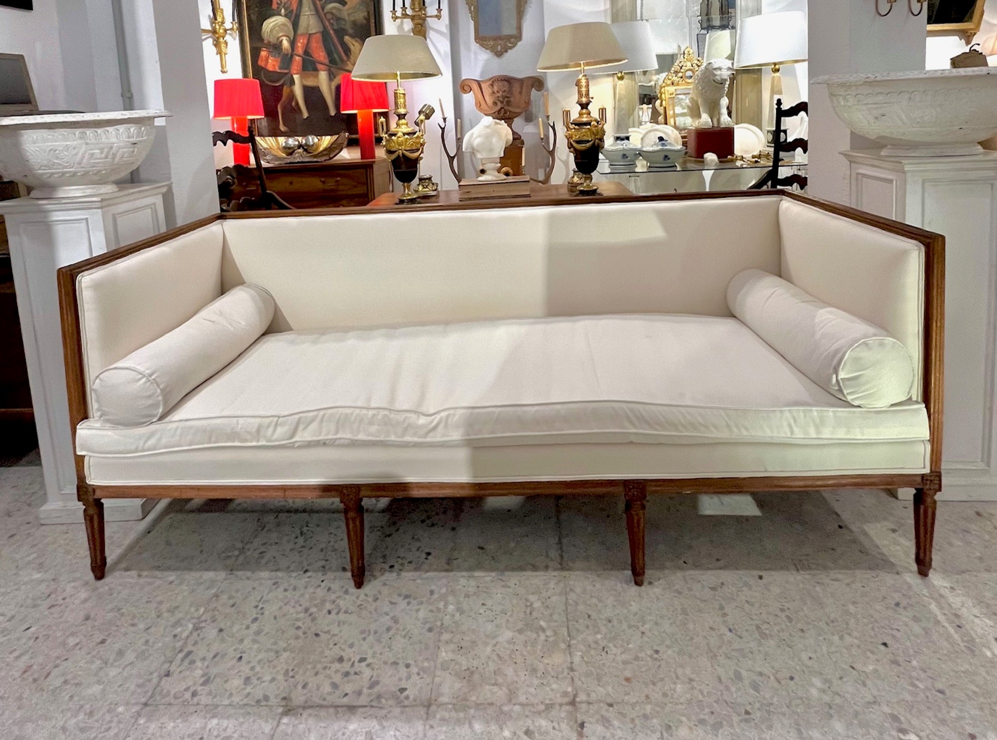 Three-seater sofa with straight lines and a classic French design, inspired by the Louis XVI-Directoire style (late 18th century). Its solid wood frame with a natural finish supports ivory or ecru linen upholstery, which adds elegance and