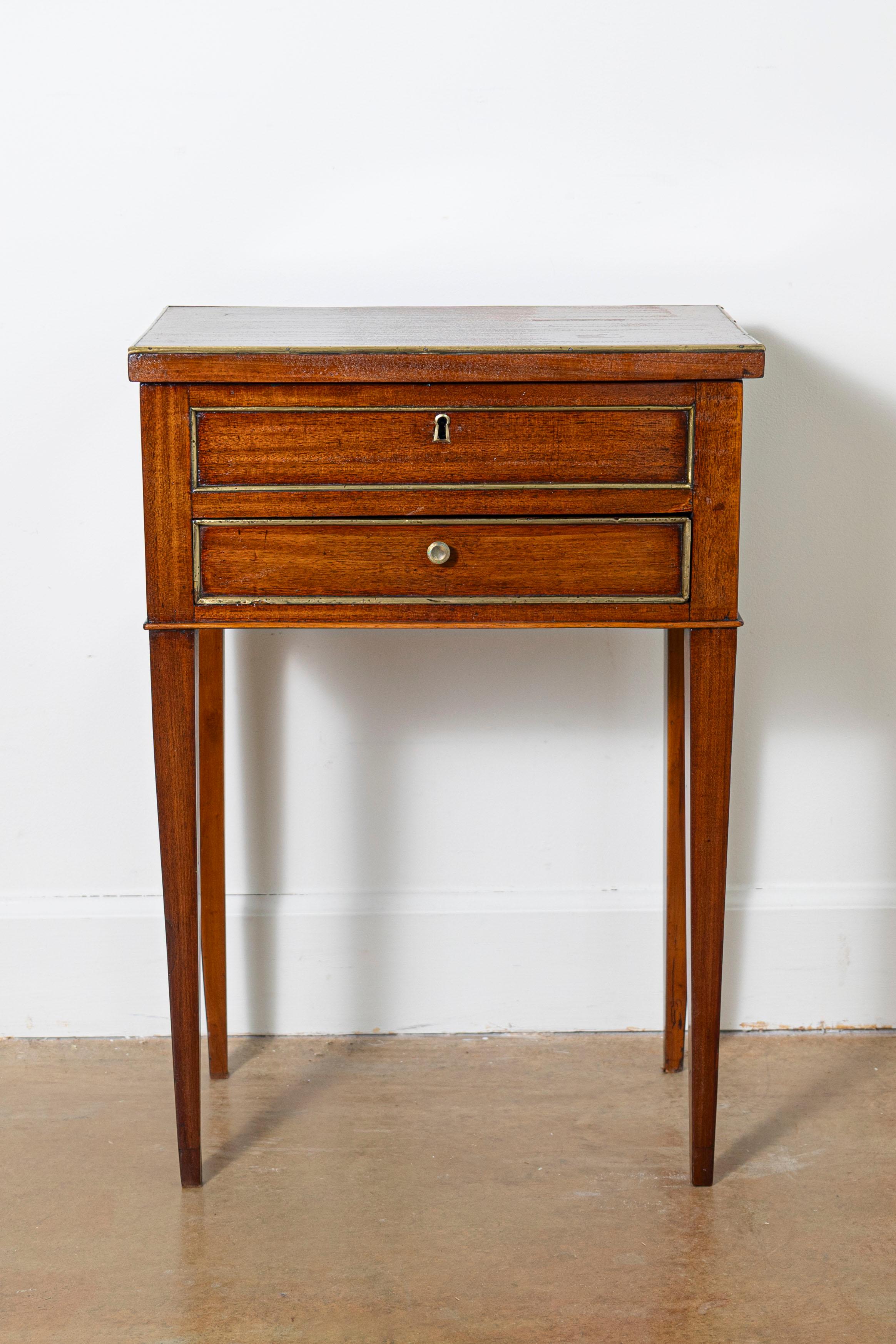 This exquisite 18th-century French dressing table showcases the refined elegance of the Louis XVI period. Crafted from mahogany, its clean lines are accented with delicate brass inlays, emphasizing its understated sophistication. The hinged top