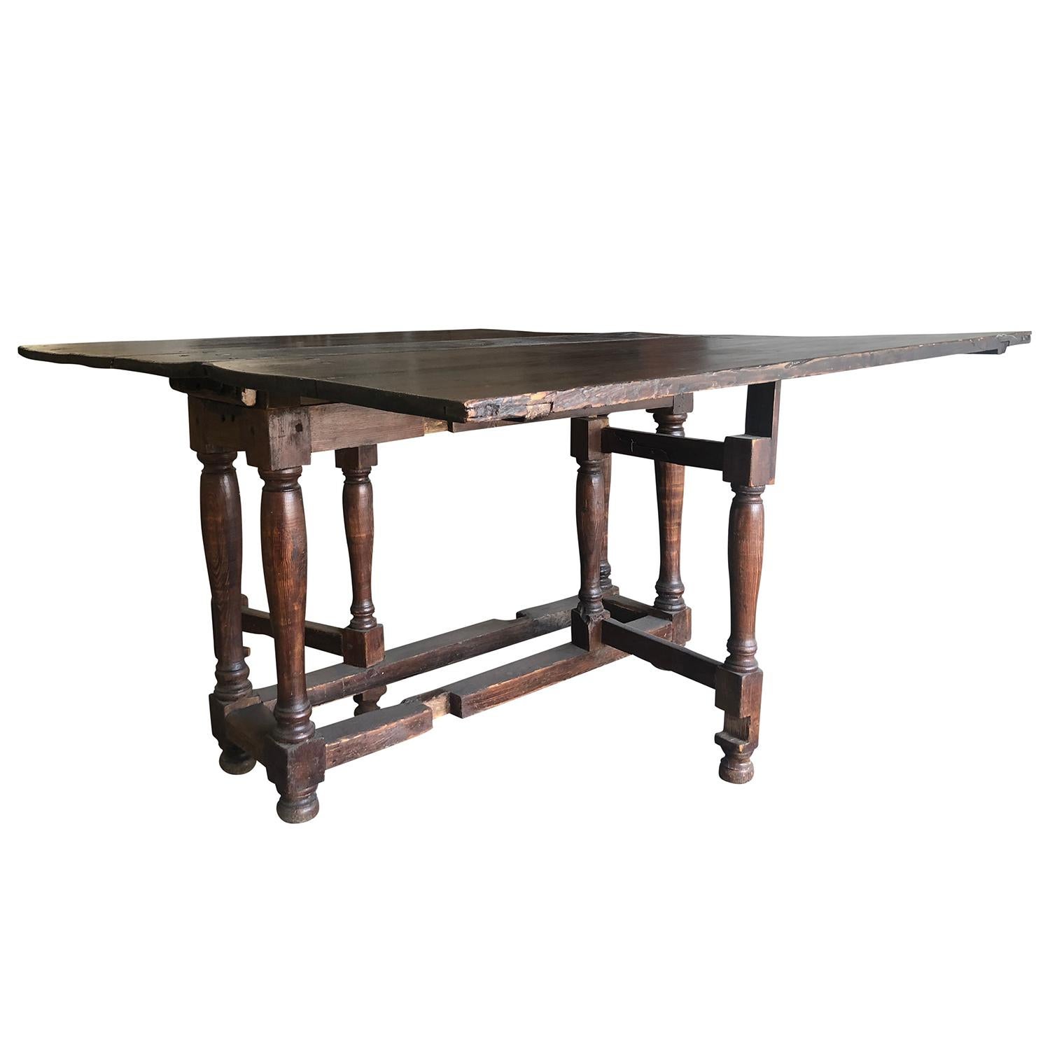 An antique French drop-leaf table from a farmhouse in Normandy, France. Made of hand crafted Walnut with a rustic finish, in good condition. Minor fading, scratches due to age. Wear consistent with age and use. Circa 18th Century, France.
