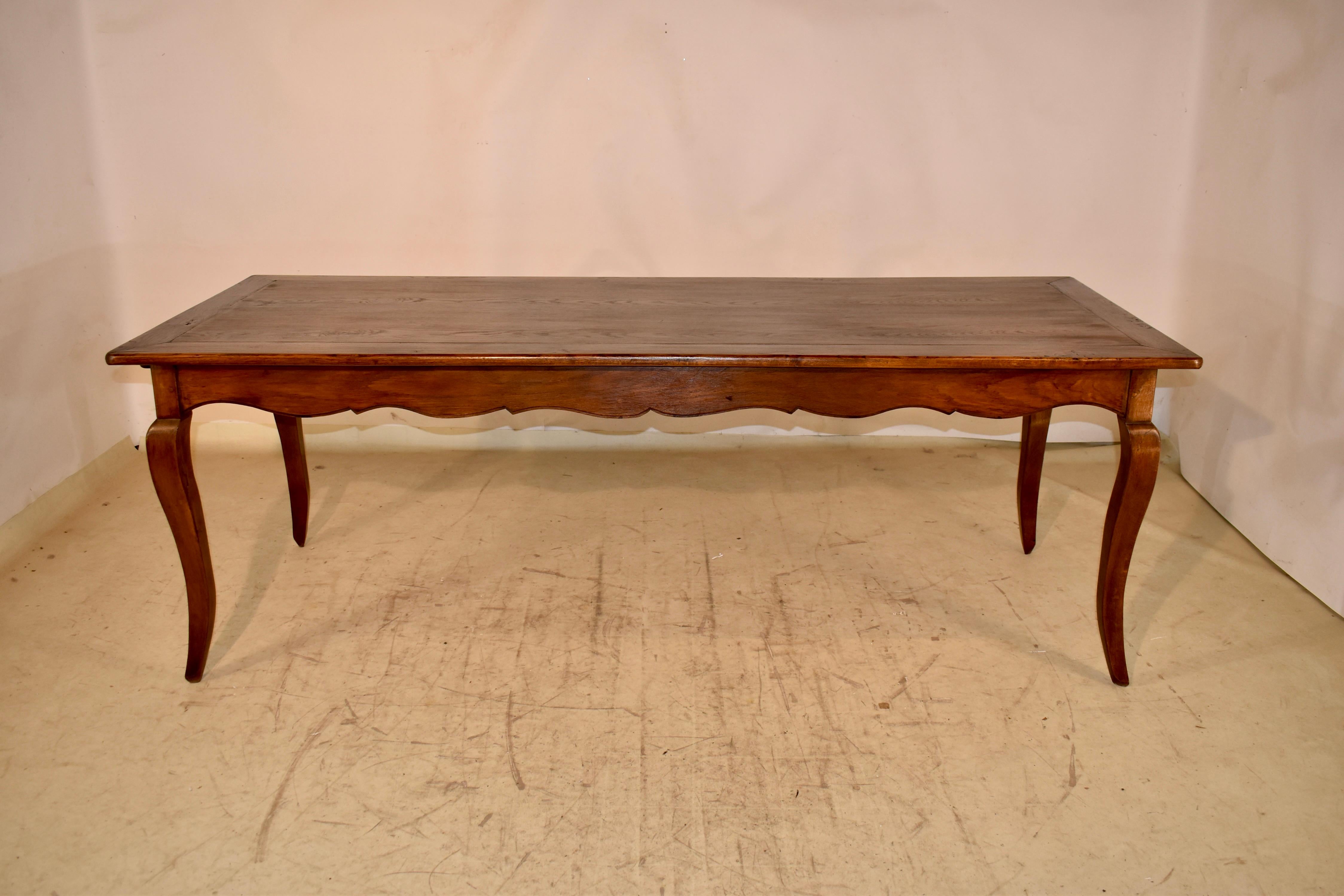 Late 18th century fabulous and large elm farm table from France.  The top is banded all the way around and has pegged construction.  This follows down to a hand scalloped apron, which contains a drawer on one end and a bread board on the other.  The