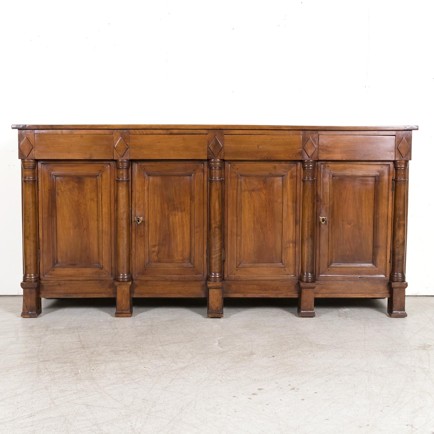 A stunning 18th century French Empire period enfilade buffet, circa early 1800s, handcrafted of solid walnut by talented artisans in Lyon, the culinary capital of France, renowned for its furniture production during the 18th century. Its style is