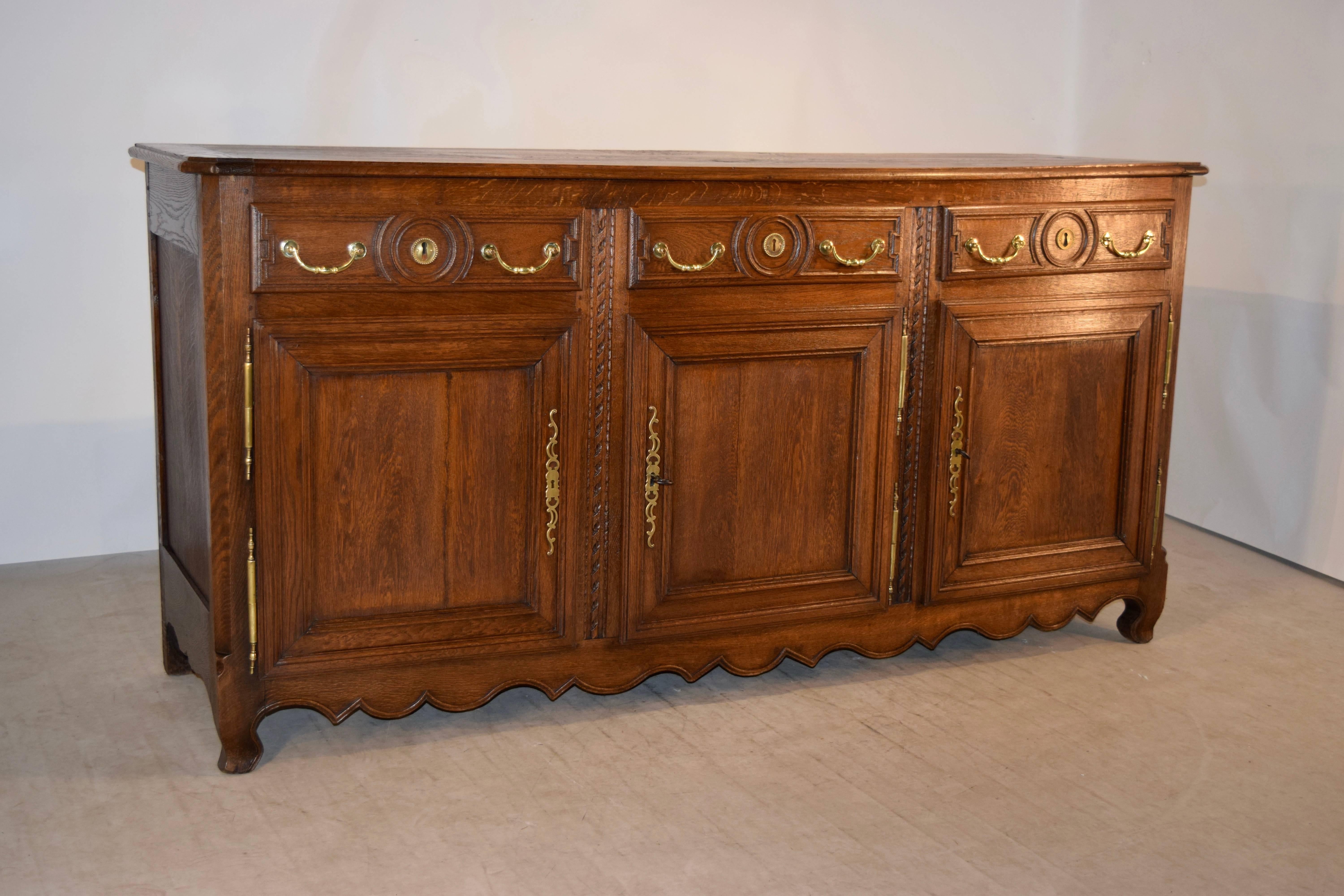 18th century oak enfilade from France. The top is made of three boards, and has banded ends and a beveled edge, following down to paneled sides and three drawers over three doors in the front, which open to reveal storage. The drawer fronts and