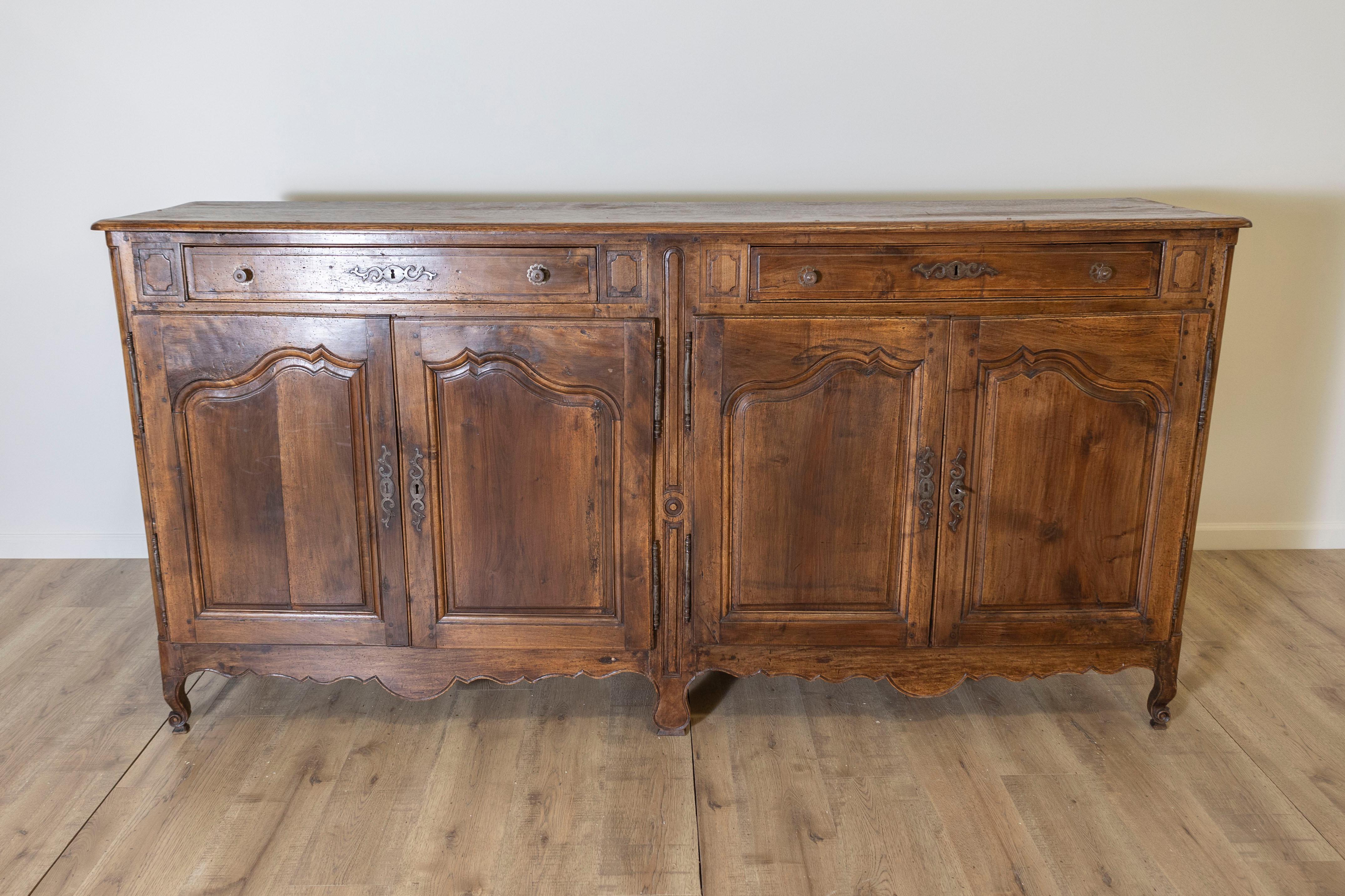 Questa eccezionale enfilade francese del XVIII secolo è uno splendido esempio di stile Luigi XV, che mette in mostra l'eleganza e la maestria dell'epoca. Realizzata in noce massiccio, l'enfilade presenta una patina ricca e calda che mette in risalto