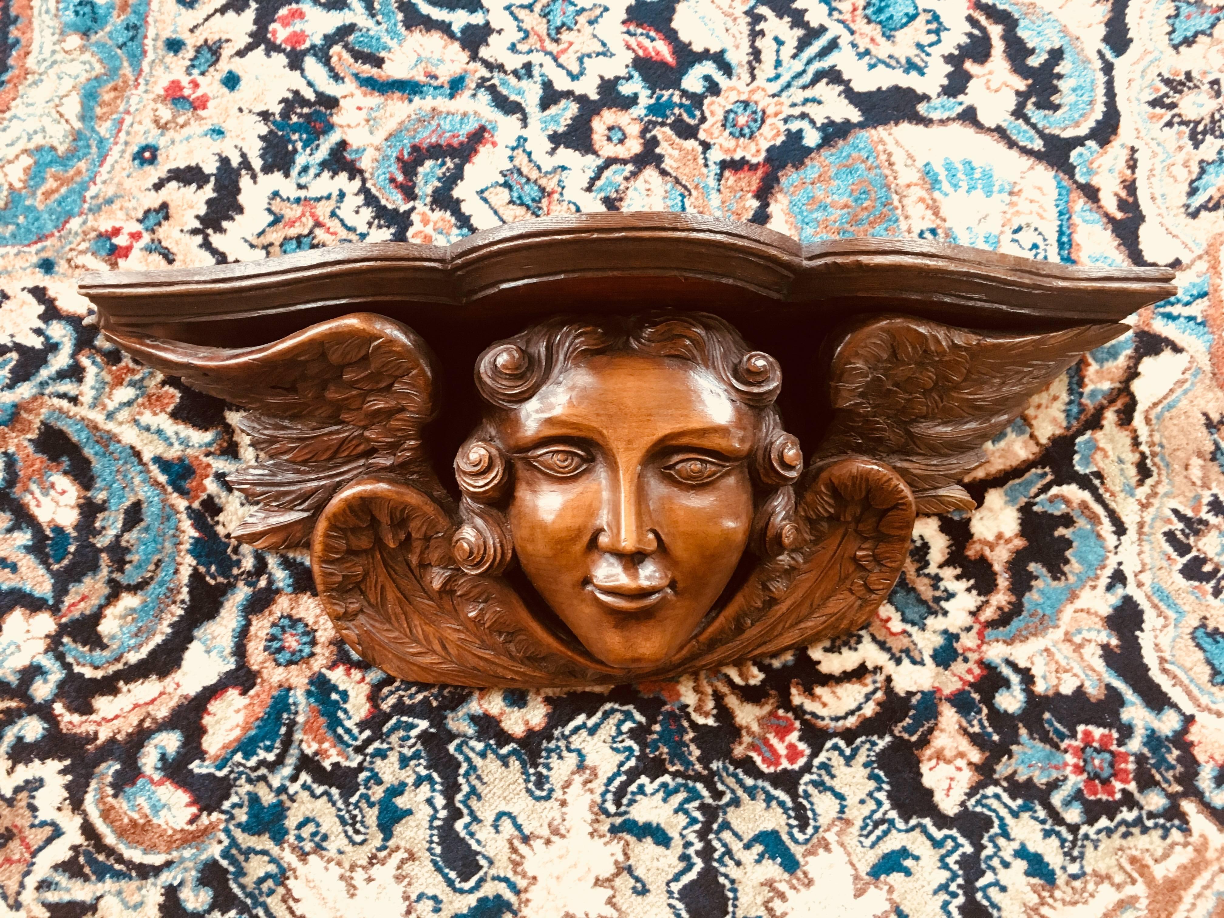 18th century walnut sculpture of an angel's head surrounded by four wings, that could be used as a small shelf.
Made in France, circa 1780.