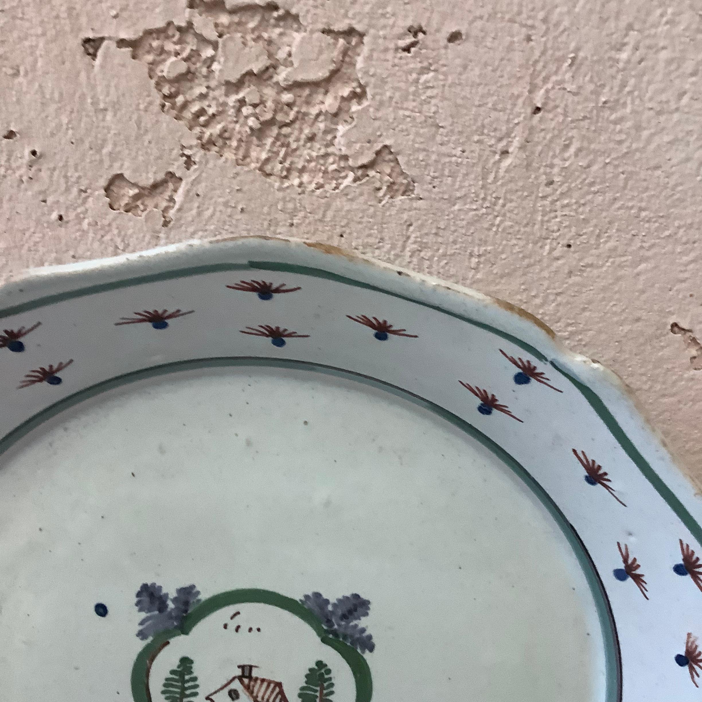 18th century French faience Nevers plate.
House with trees on the center.
Border with flowers.