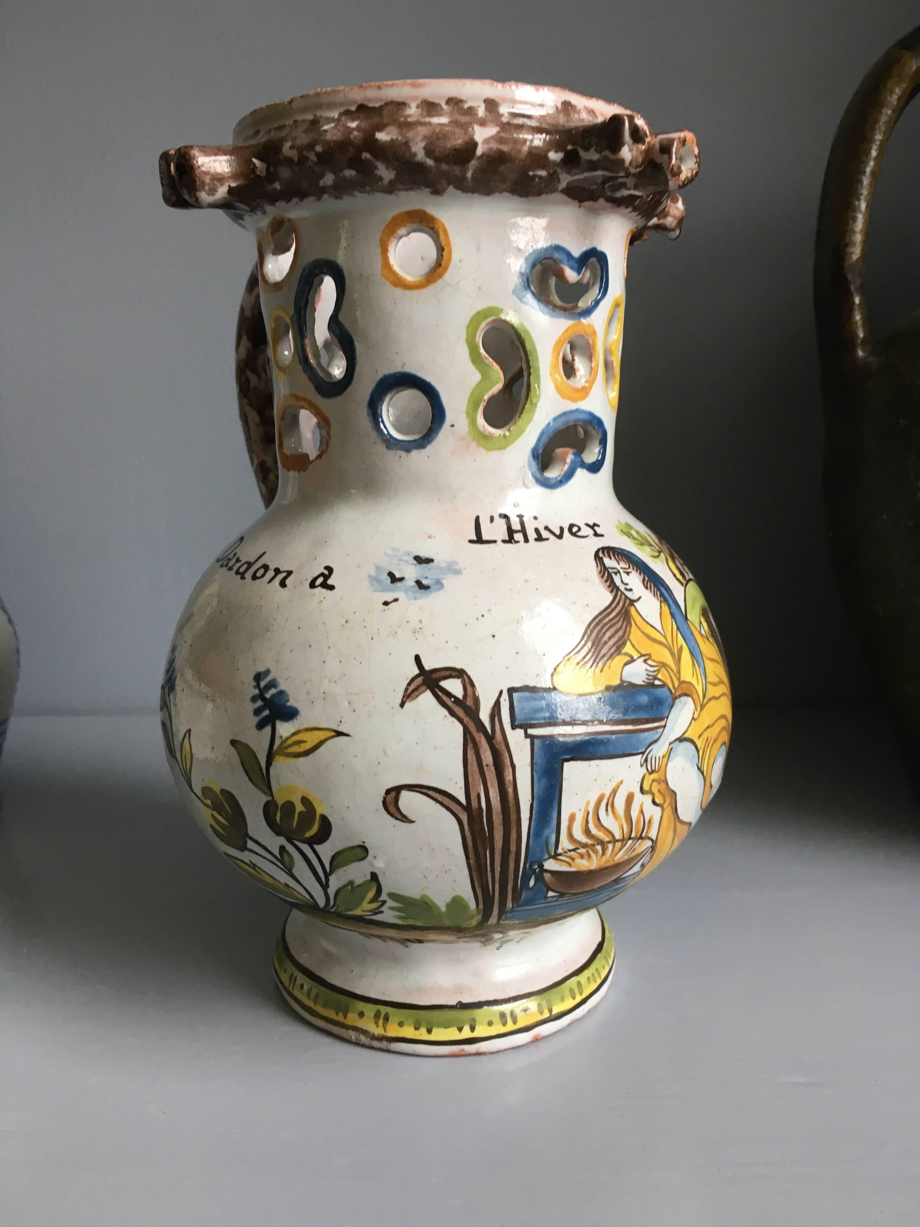 A charming 18th century faience “pichet trompeur” from the town of Nevers. The jug is decorated with a glazed scene of a woman seated before a fireplace with the word ”L’Hiver” (the winter) and flanked with two names Jules Dardon a Pierre Veron. The