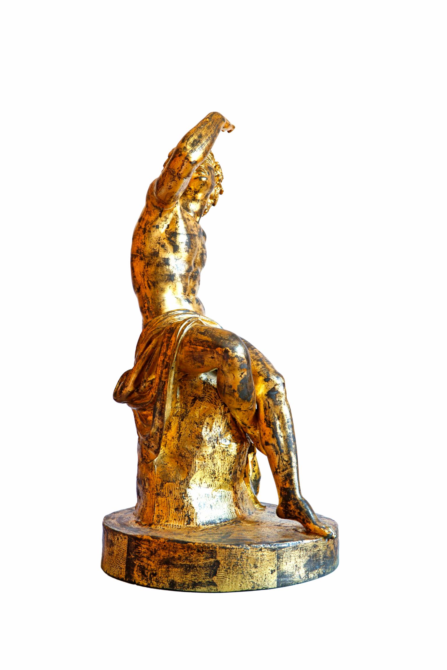 French gilt zinc figure of Bacchus modelled as seated on a tree trunk with one raised arm. On an oval plinth.