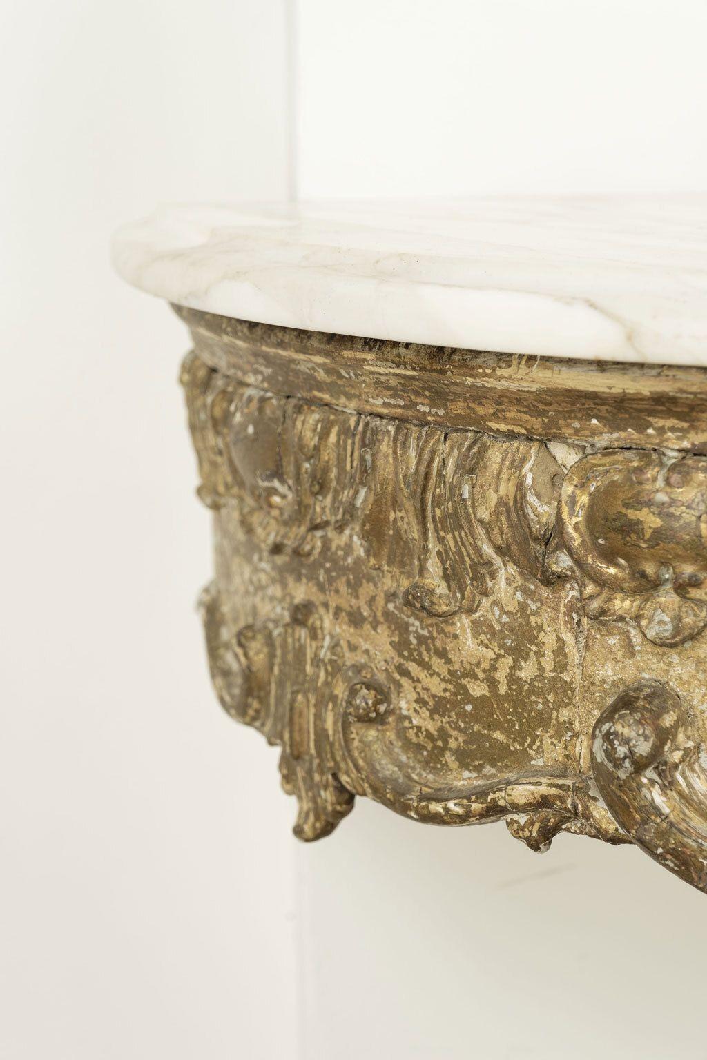 18th century French giltwood console circa 1740-1770. Extremely well-executed wall-mounted console hand-carved in giltwood with demilune Carrara marble top.

Note: Regional differences in humidity and climate during shipping may cause antique and