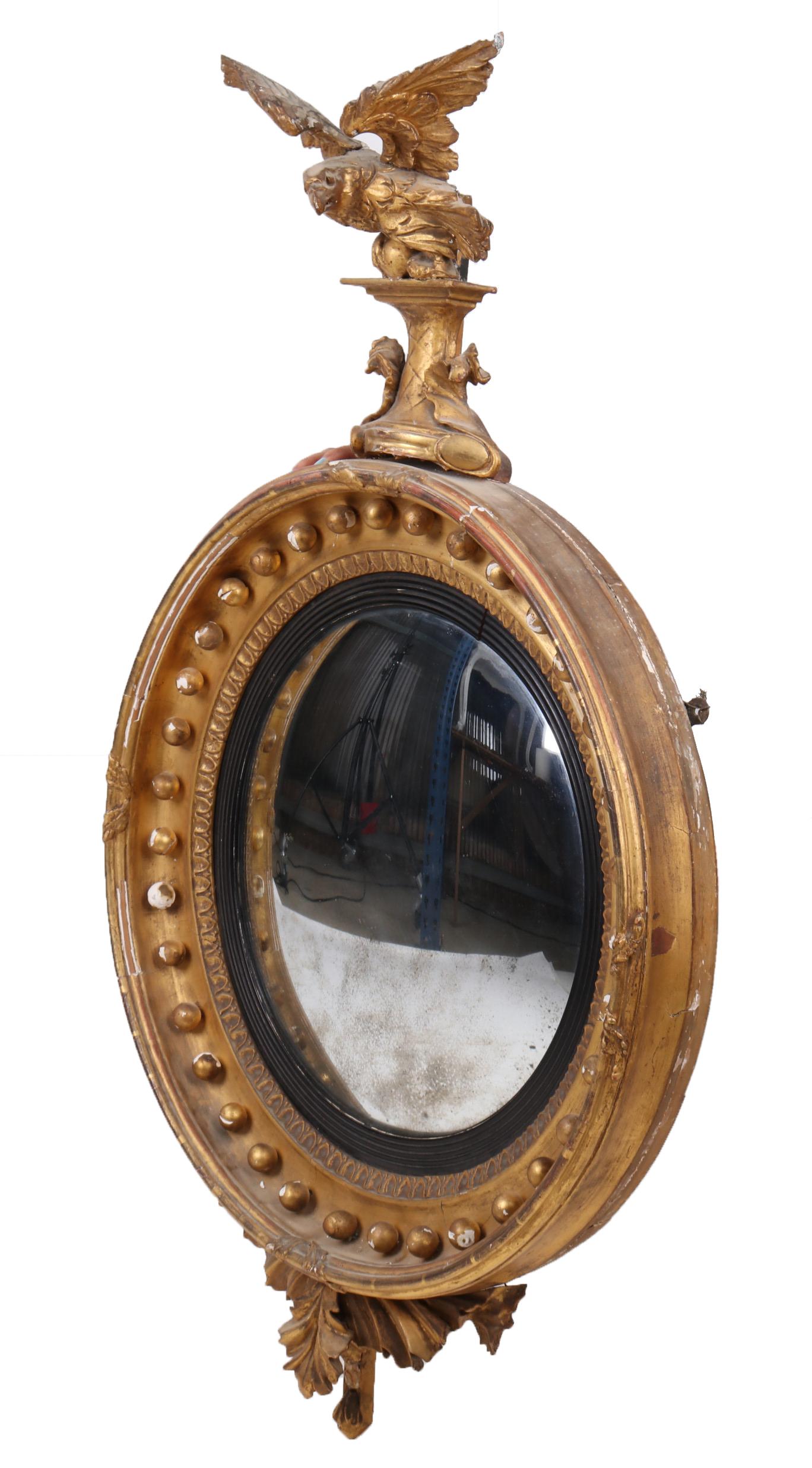 18th century French golden Regency convex mirror topped by an eagle.