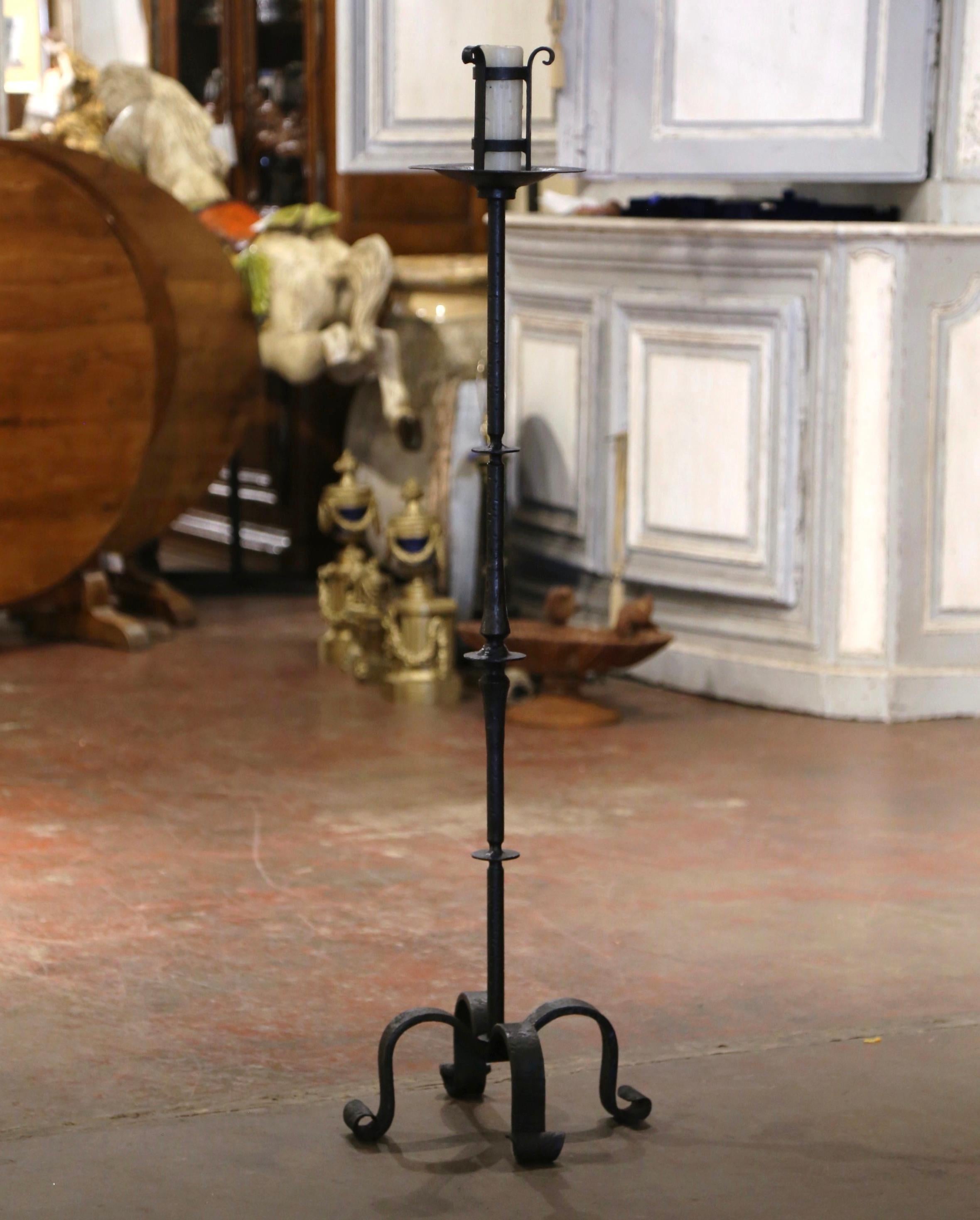 Realizzato in Francia intorno al 1780 e forgiato in ferro massiccio, il portacandele poggia su quattro gambe a voluta su un fusto centrale tornito e decorato con alcuni dischi ornamentali. L'alto candelabro da terra in ferro battuto è abbellito sul