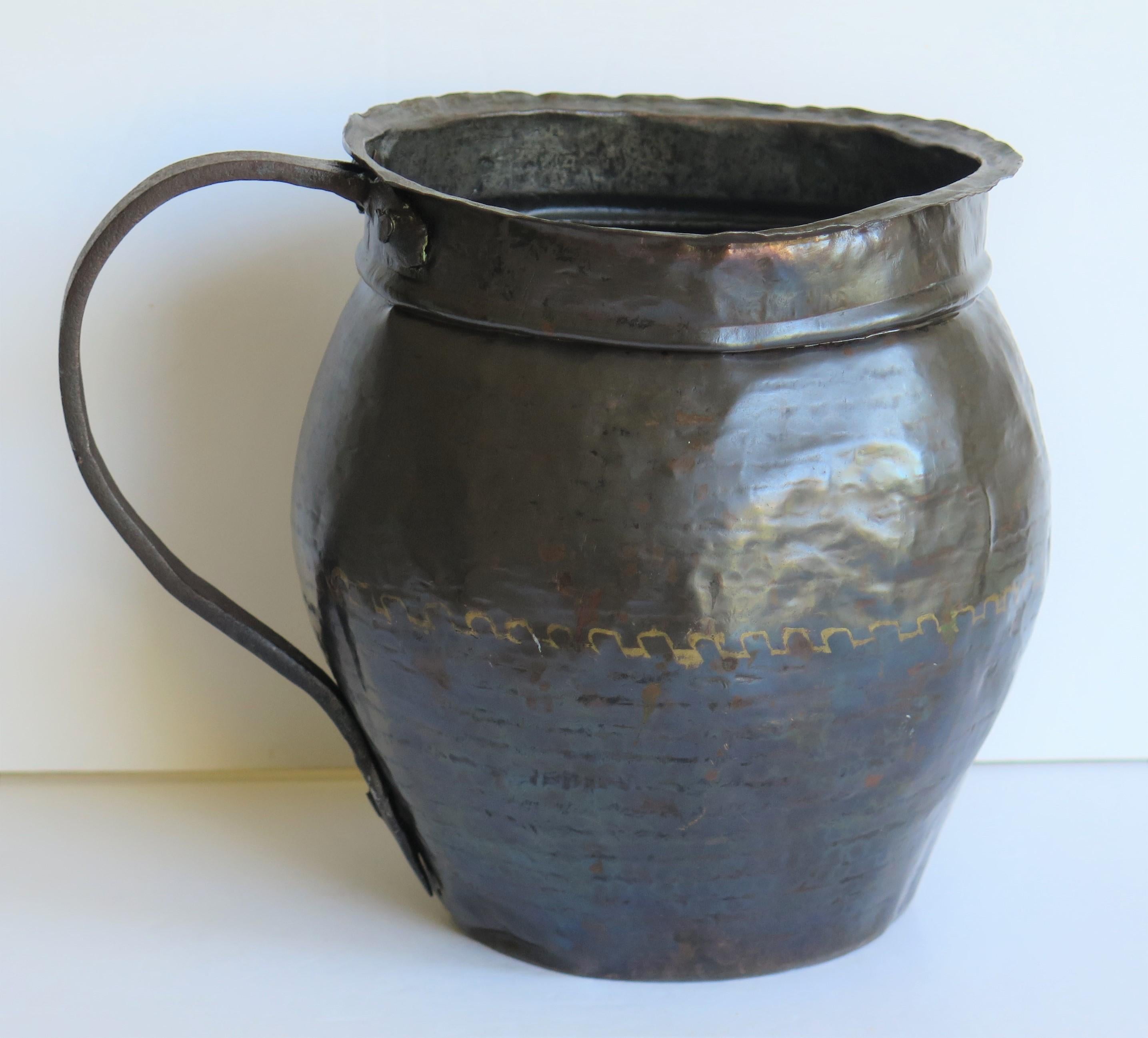 This is an interesting 18th century, French, hammered copper jug or pitcher with an iron loop handle.

The jug or pitcher is all hand made with a hammered copper body and formed rim with an iron loop handle riveted to the body. The jug body is