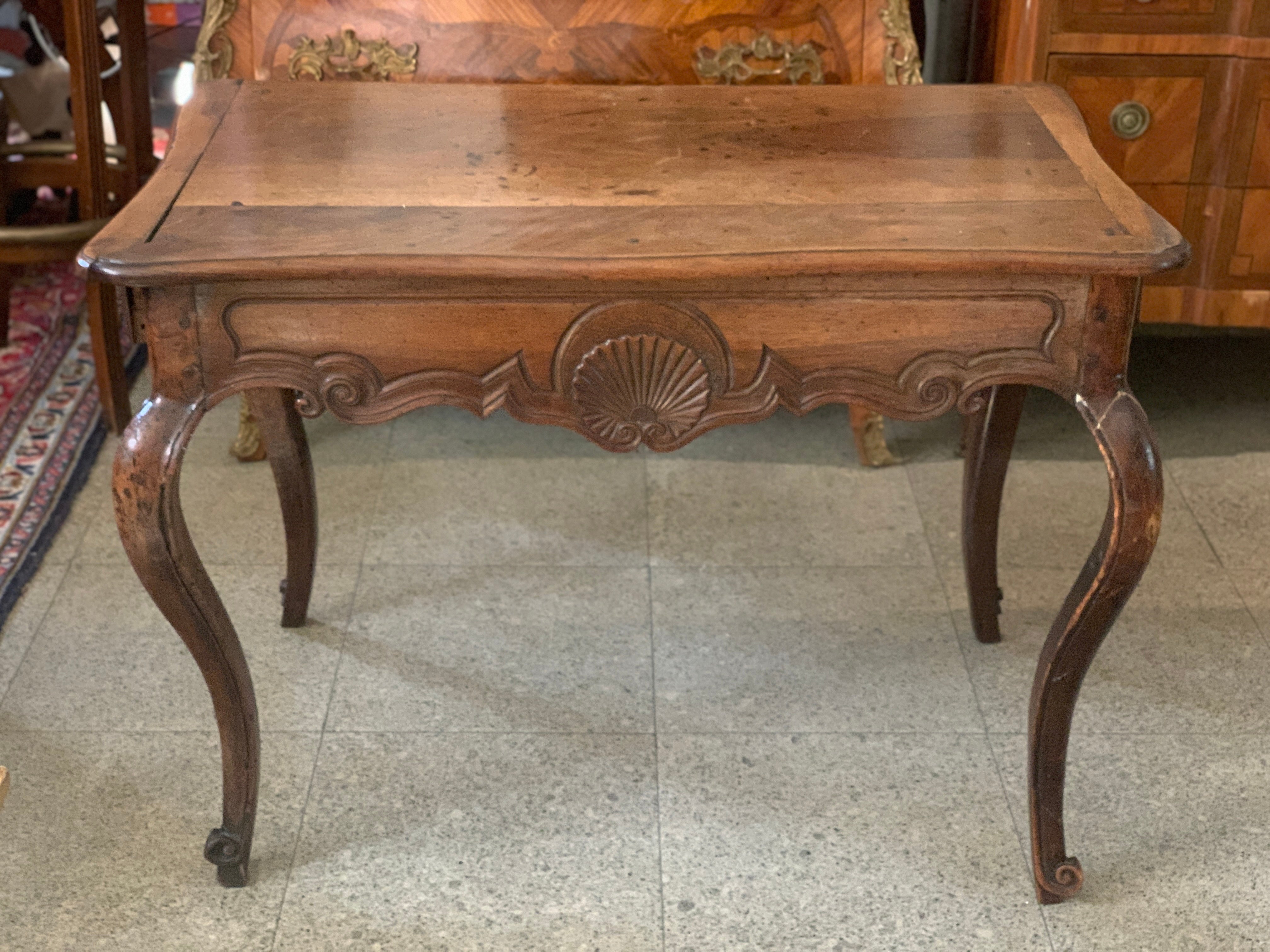 18th century French hand carved walnut writing table with two side drawers resting on curved decorated legs. The table is in it authentic condition with no restorations made. The condition is quite good according to the age and use of the piece.