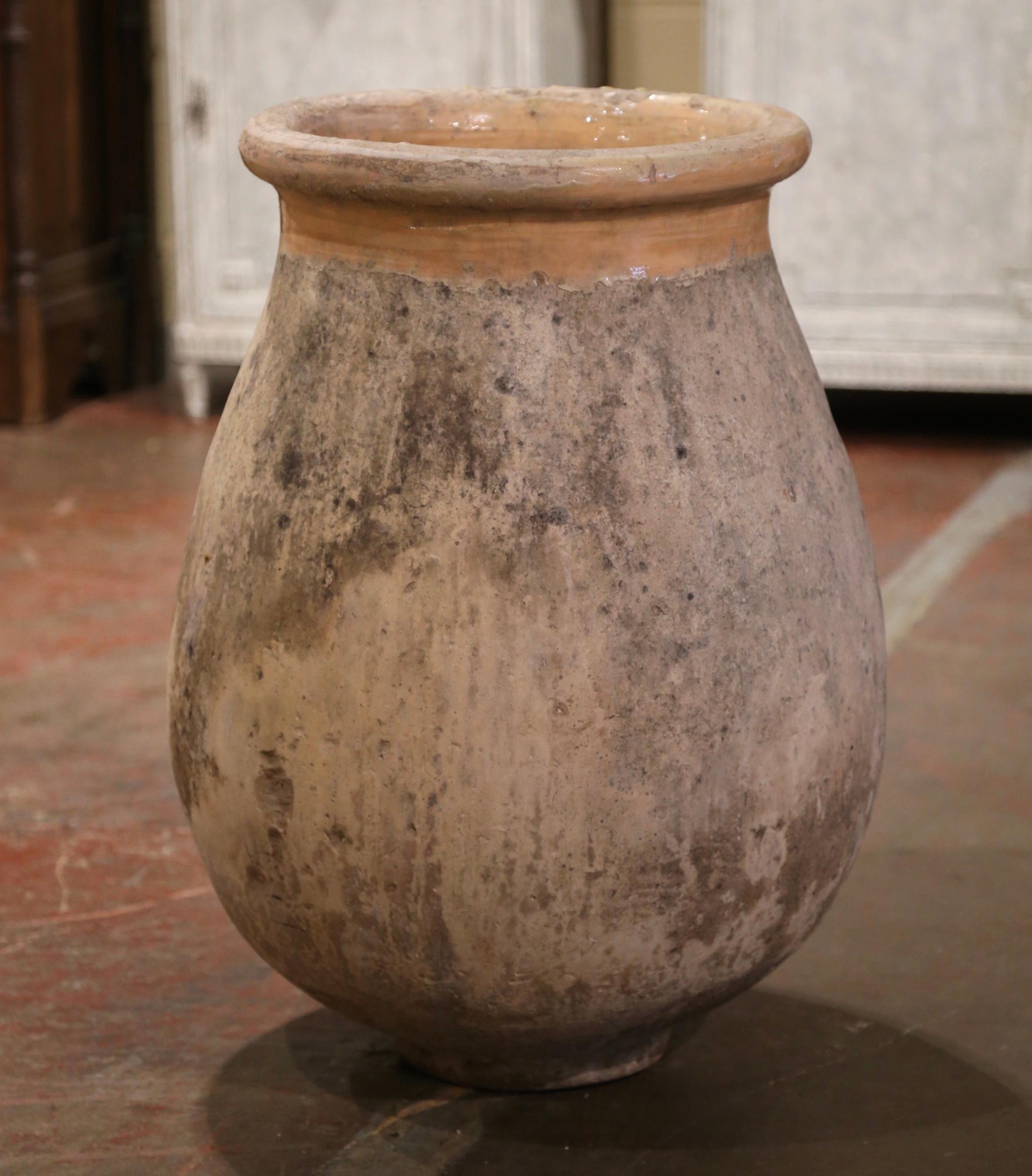 Cette grande jarre à olives ancienne en faïence a été créée à Biot, dans le sud de la France, vers 1760. Fabriqué en argile blonde et de couleur neutre, le vase en terre cuite a une forme ronde et bulbeuse traditionnelle. Ce pot rustique et usé par