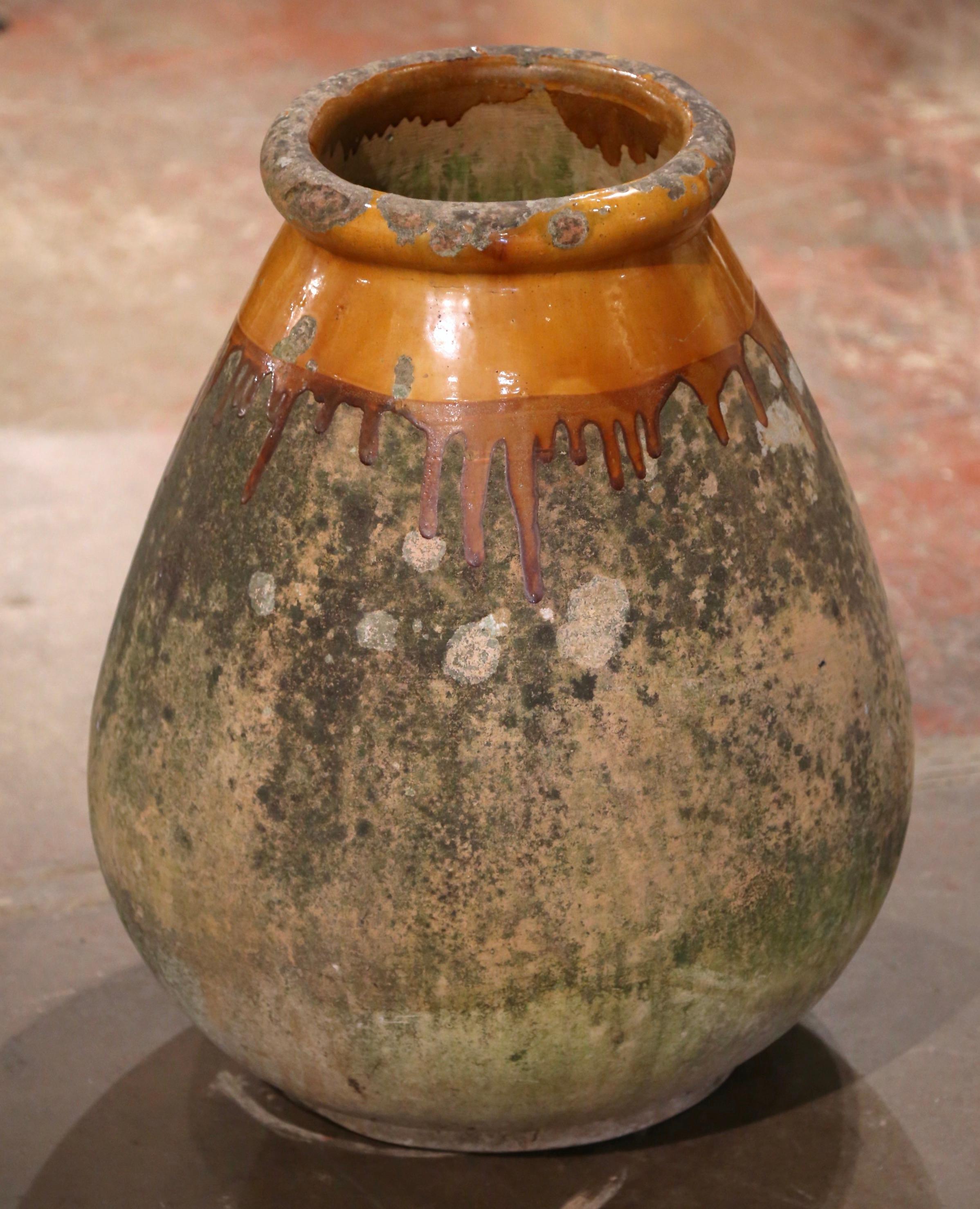 Cette grande jarre à olives ancienne en faïence a été créée à Biot, dans le sud de la France, vers 1760. Fabriqué en argile blonde et de couleur neutre, le vase en terre cuite a une forme ronde et bulbeuse traditionnelle. Ce pot rustique et usé par