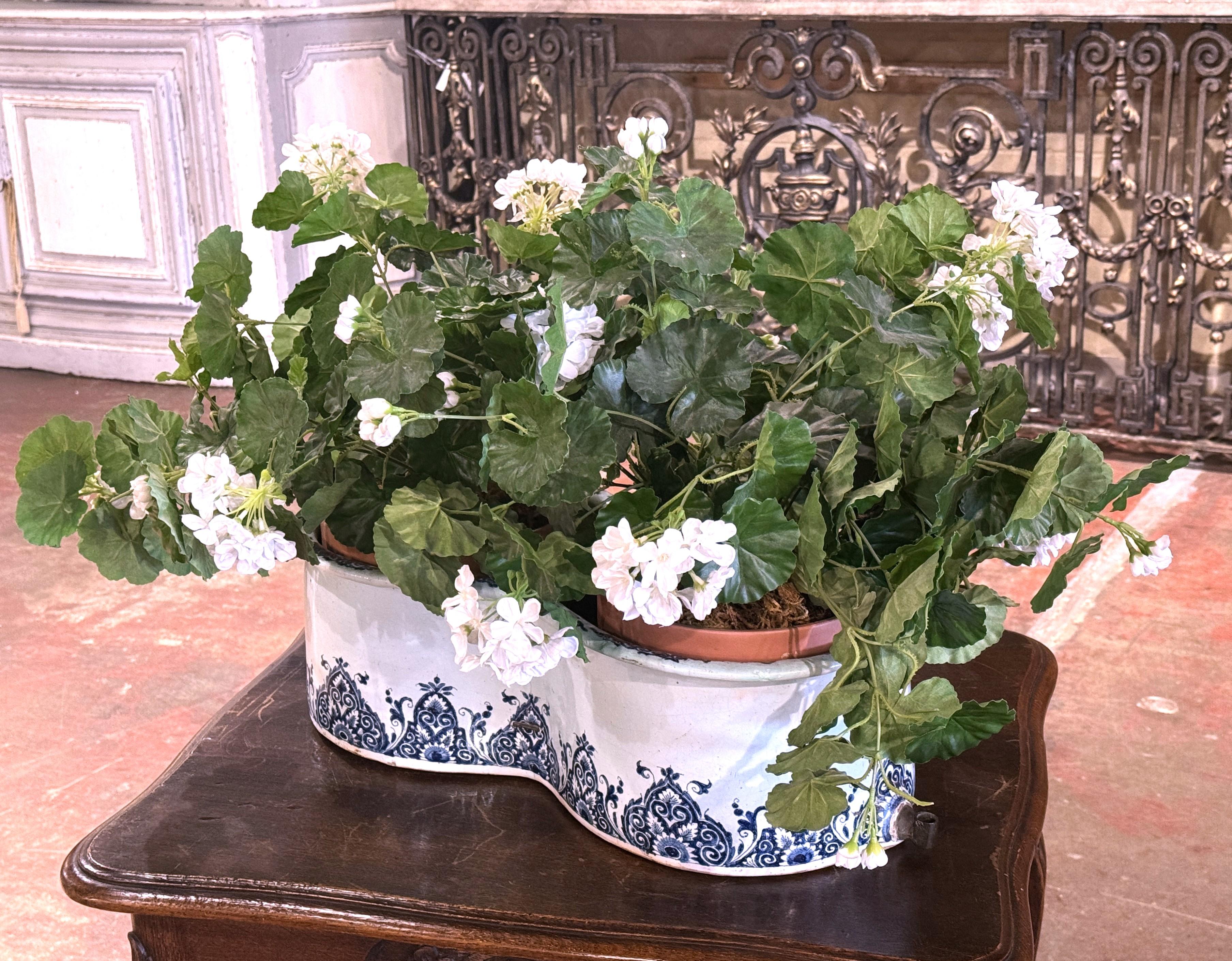 Use this colorful antique bidet as a jardiniere or planter! Crafted in France circa 1780, and double-oval or figure-eight form shape, the planter is decorated with blue floral and scroll patterns on a white or light cream background, giving it a