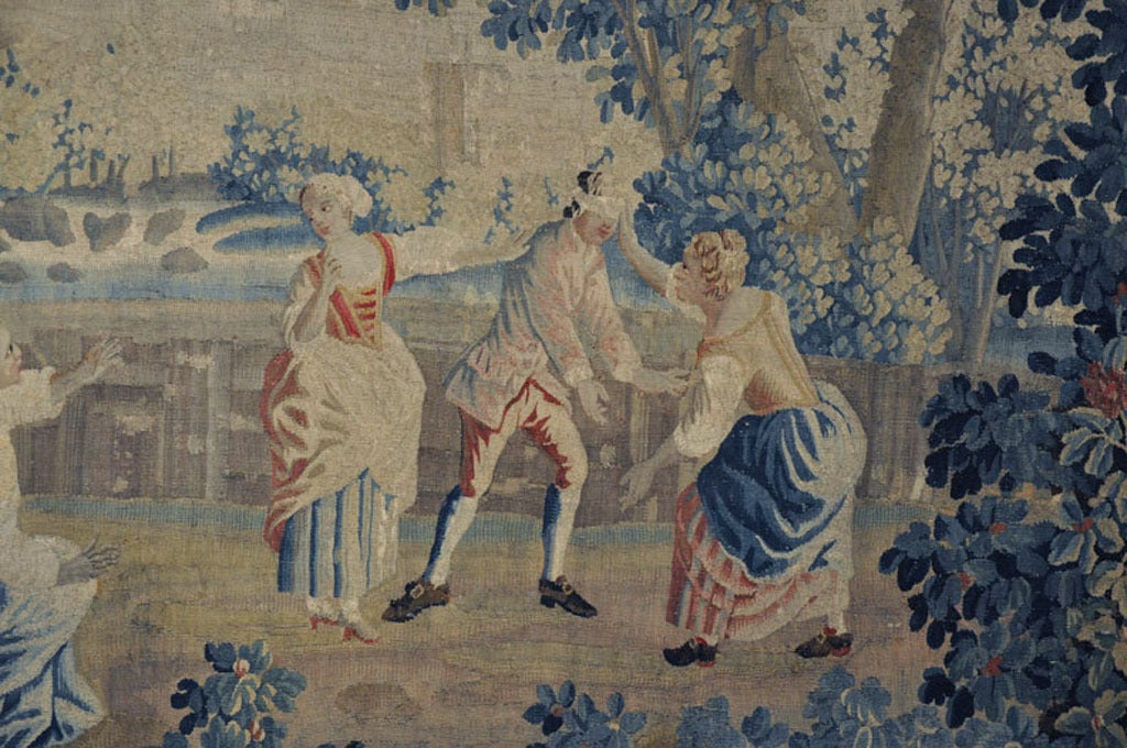 Cette grande tapisserie ancienne a été tissée à Aubusson, en France, vers 1760. La scène colorée représente un groupe de personnes jouant au Colin-Maillard, un jeu très populaire au XVIIIe siècle. Cette magnifique tapisserie présente de magnifiques
