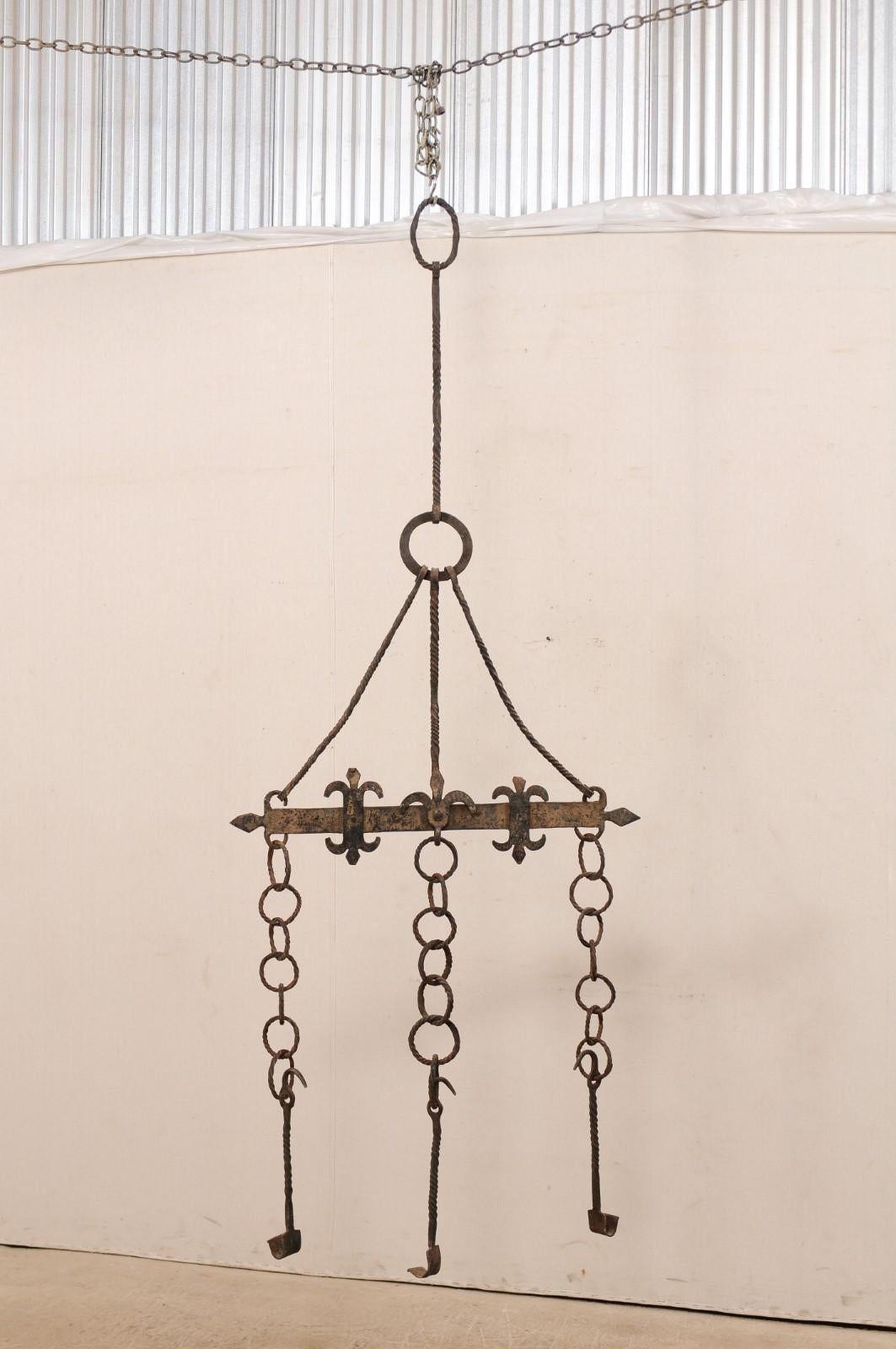 A tall French hanging iron fireplace accessory from the 18th century. This fabulous antique fireplace accessory piece from France, when hung, is approximately 7.5 feet in height and roughly 3 feet wide. It features a horizontal bar, adorn in