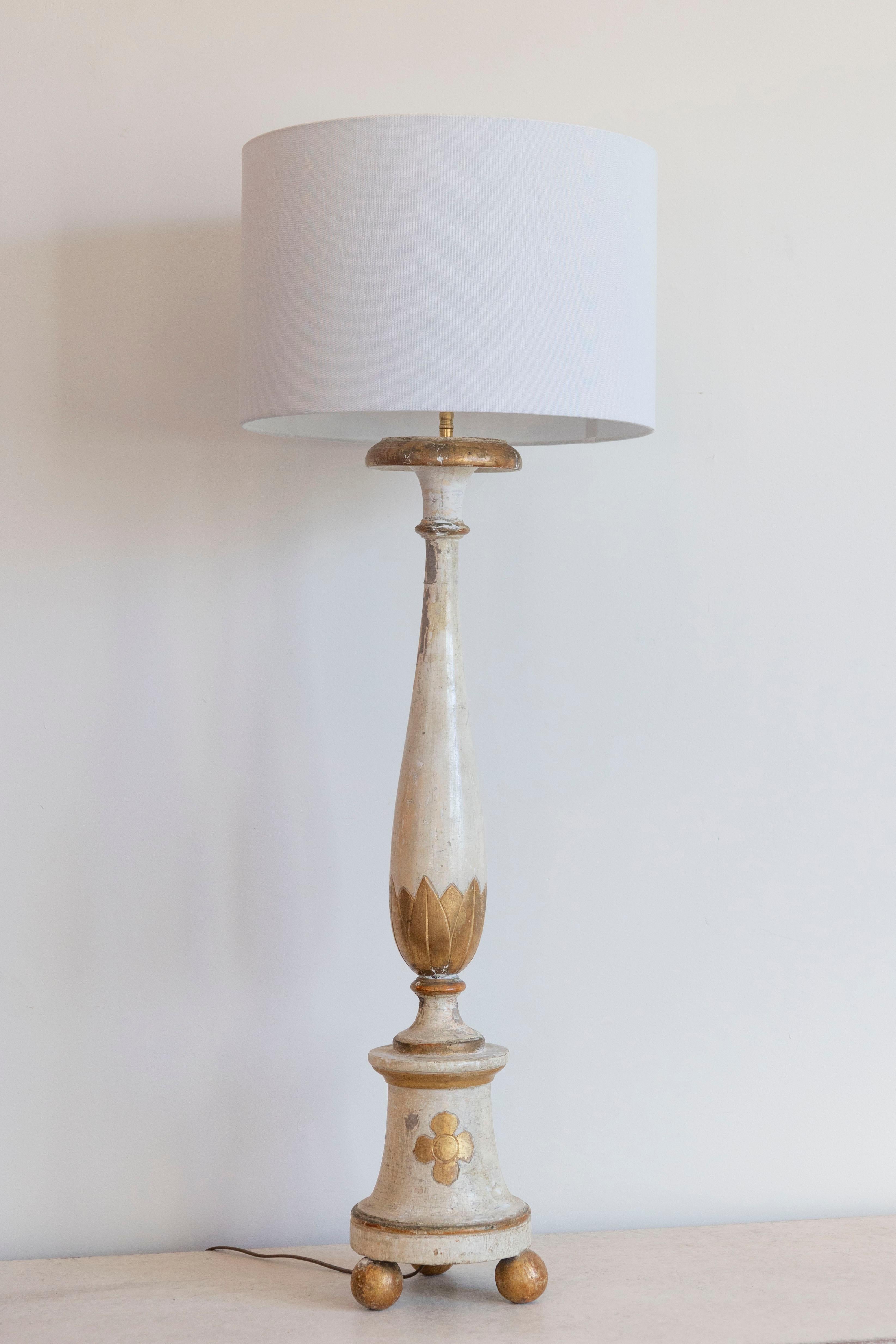 Esta exquisita lámpara de mesa francesa del siglo XVIII es un magistral ejemplo de la artesanía de la época de Luis XVI, fabricada originalmente como candelabro y convertida después en lámpara. Fabricada en madera tallada a mano, presenta un acabado