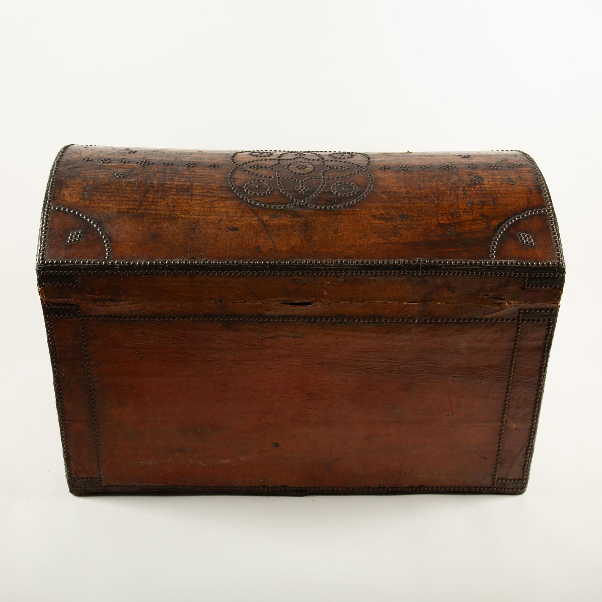 Un coffre provincial substantiel en chêne recouvert de cuir ambré richement patiné et orné sur chaque face de motifs élaborés de têtes de clous (clouté) - spirales, losanges et bandes de bordure exécutées par des centaines de clous en laiton. Le