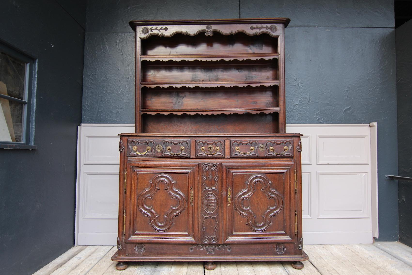 French buffet (Vaisselier) made of oak, Lorraine, circa 1780.

Consisting of a base cabinet with 2 doors and 3 drawers above, as well as a shelf.
Body with rounded corners, partially carved. Profiled doors on large outside brass fittings. Door