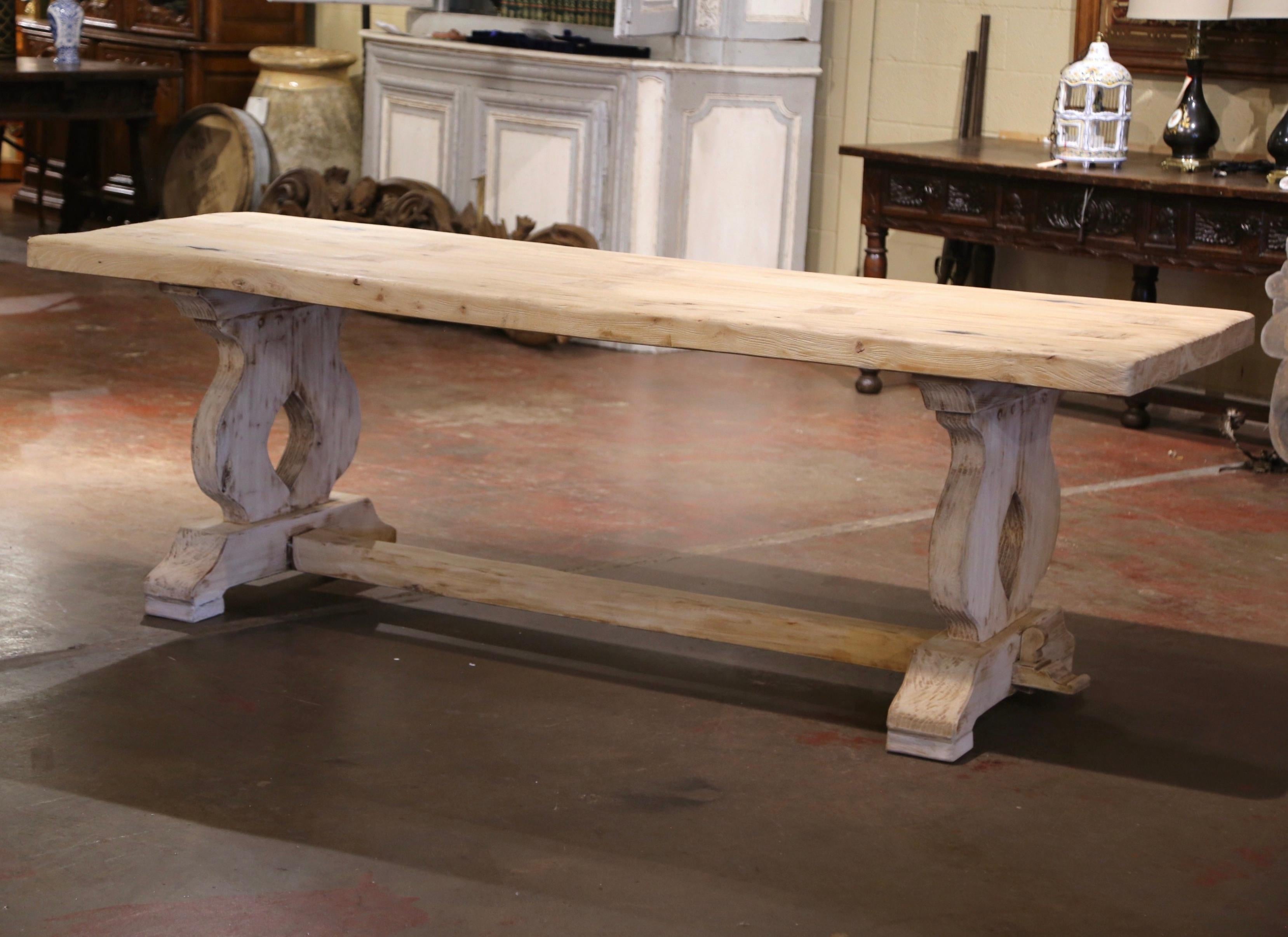 This elegant antique dining table was crafted in Normandy, France circa 1780. Built of solid oak, the monastery table stands on pierced and curved baluster support legs joined by cross stretcher with mortise and tenon joinery terminated in molded