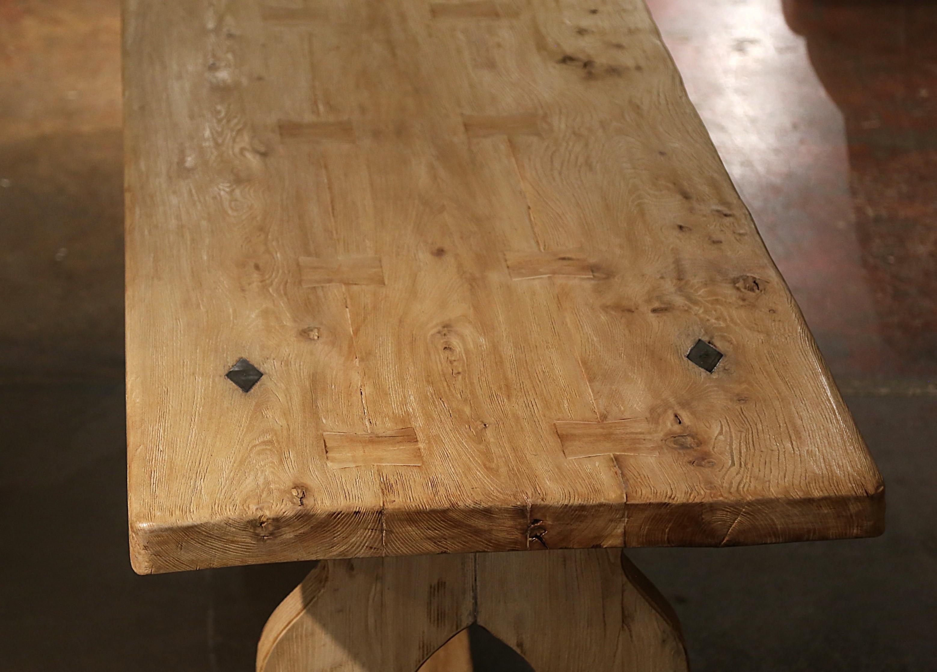 This elegant antique dining table was crafted in Normandy, France circa 1780. Built of solid oak, the monastery table stands on pierced and curved baluster support legs joined together by cross stretcher with mortise and tenon joinery, and
