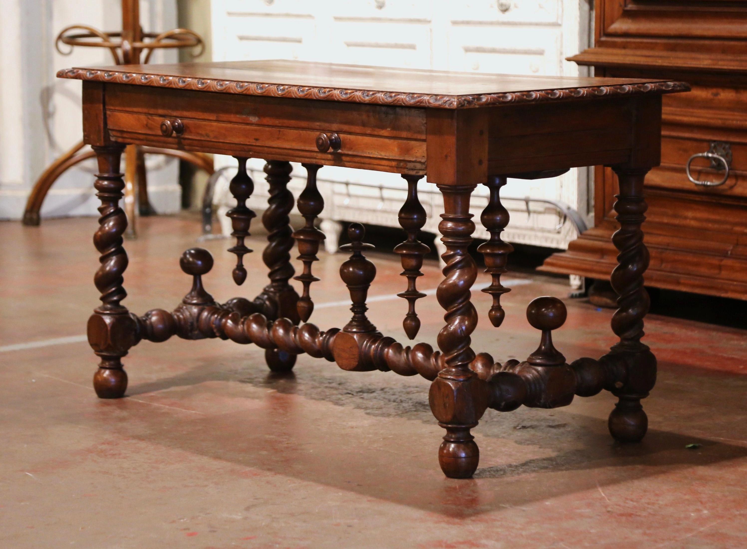 Crafted in the Perigord region of France, circa 1760, the antique writing table stands on four thick carved barley twist legs ending with bun feet, and embellished with an elegant stretcher at the base dressed with side round finials and decorated