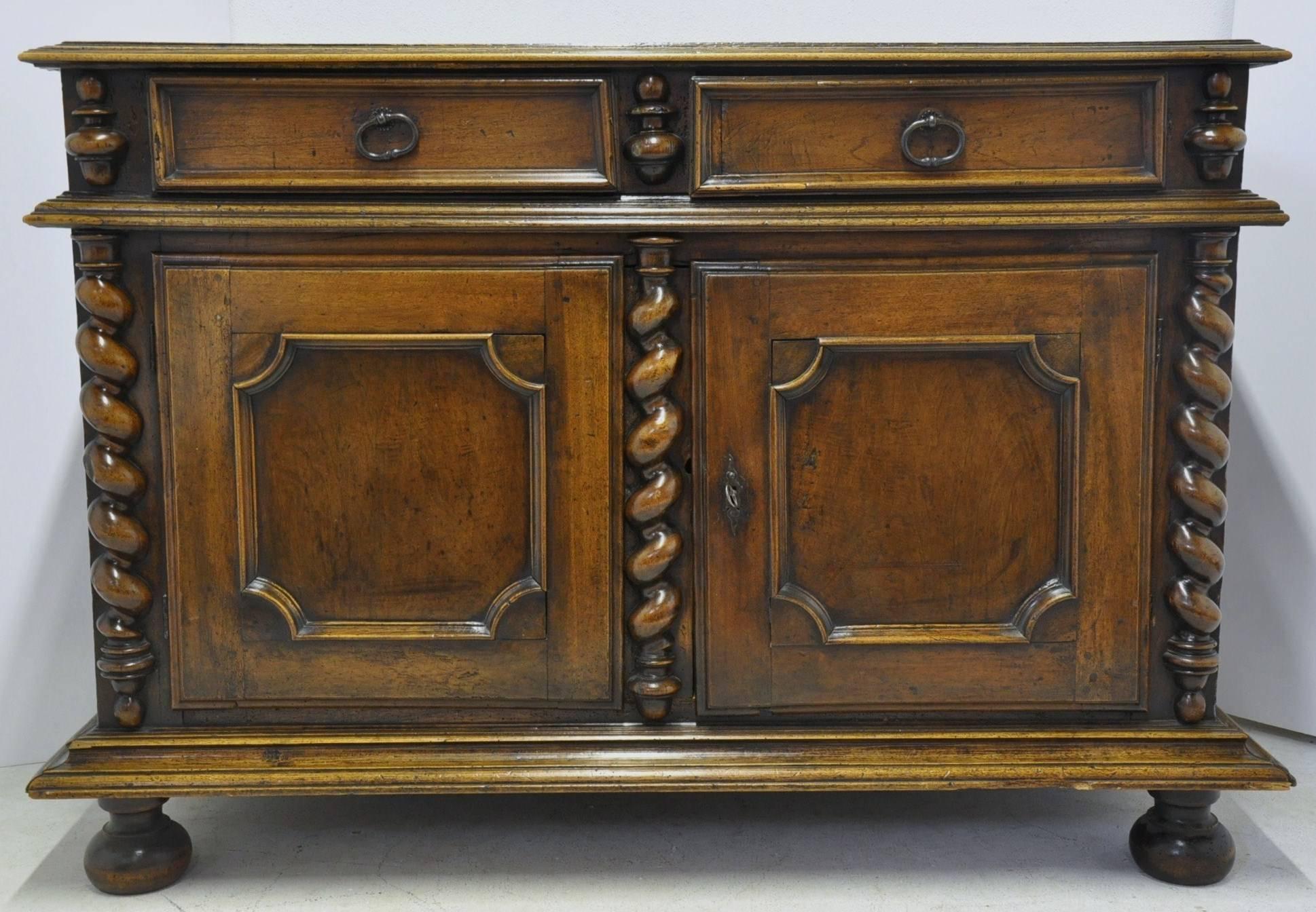 This elegant antique fruitwood buffet was crafted in southwest France, circa 1750. The cabinet stands on front bun feet over a carved plinth, and features a pair of doors with raised panels flanked with three hand carved barley twist columns on each