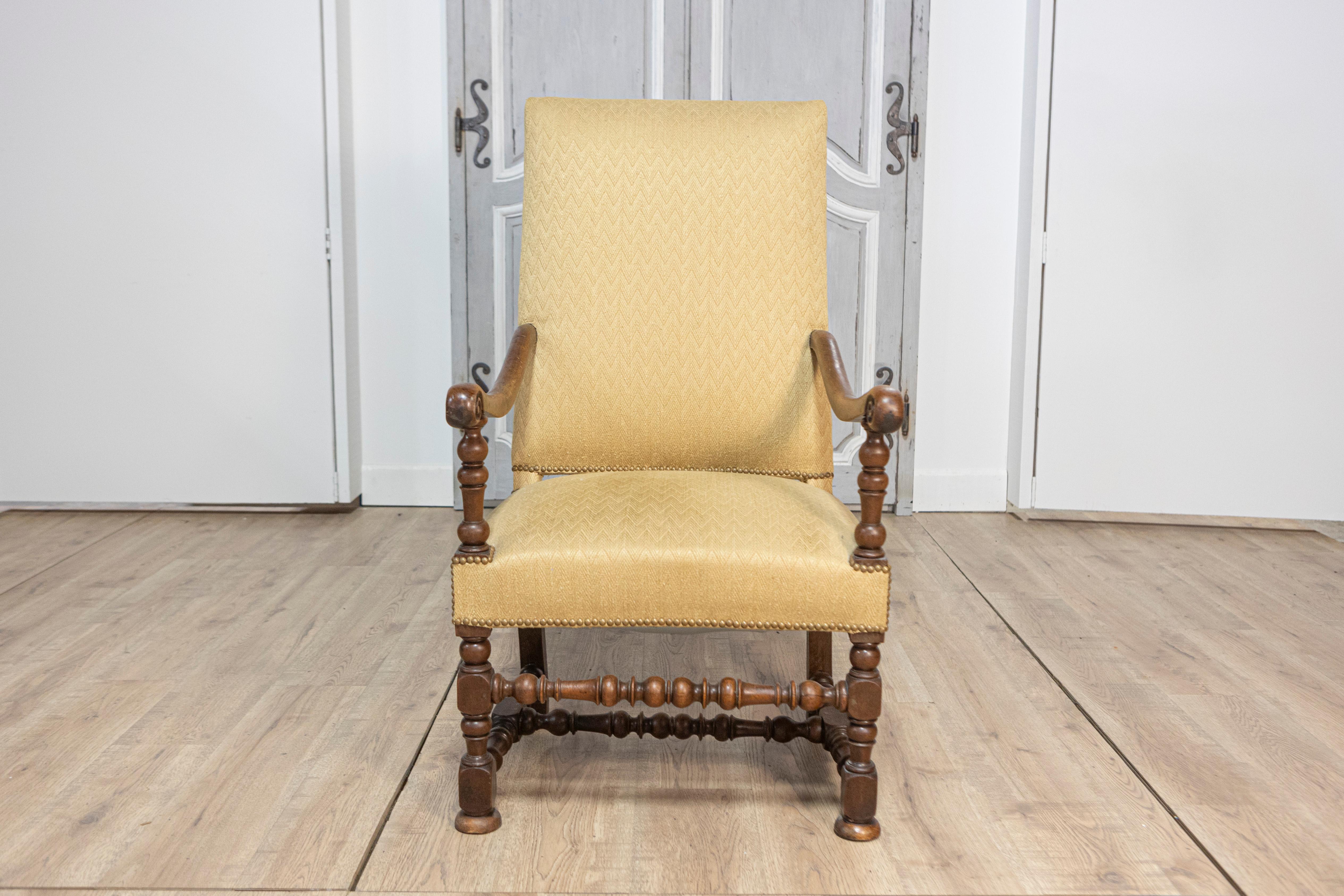 Este exquisito sillón francés del siglo XVIII, de estilo Luis XIII, muestra la artesanía intemporal y la elegancia de la época. Construida en madera de nogal, la silla presenta un marco bellamente tallado con patas, camillas y apoyabrazos