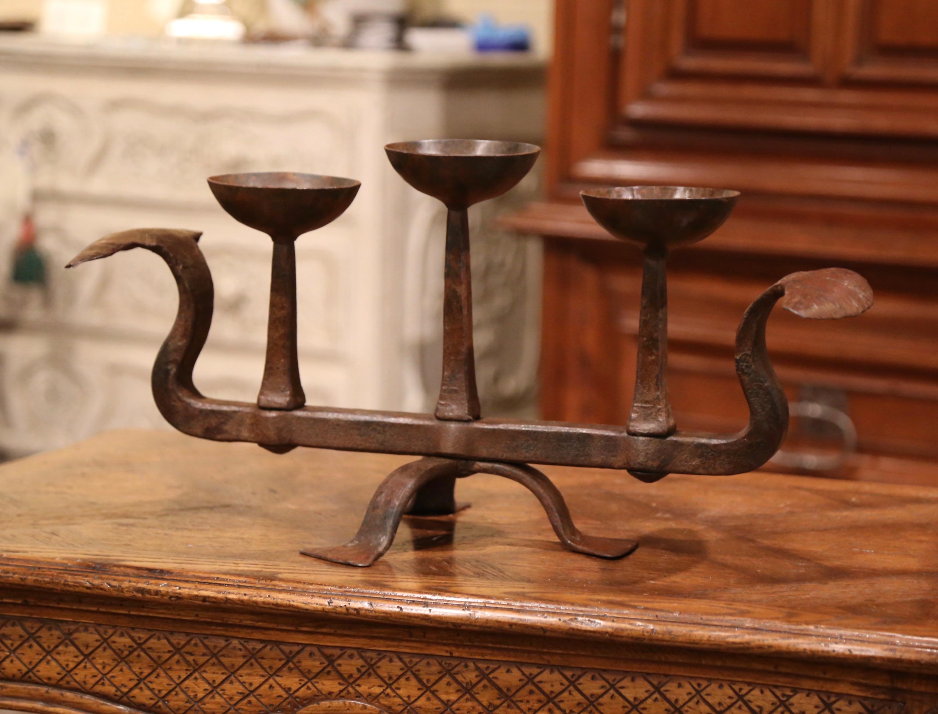 Decorate a mantel or a buffet with this elegant antique candelabra, crafted in southern France circa 1760, the forged piece stands on a three-leg pedestal and features three arms for candles decorated with round bobeches. The light is in excellent