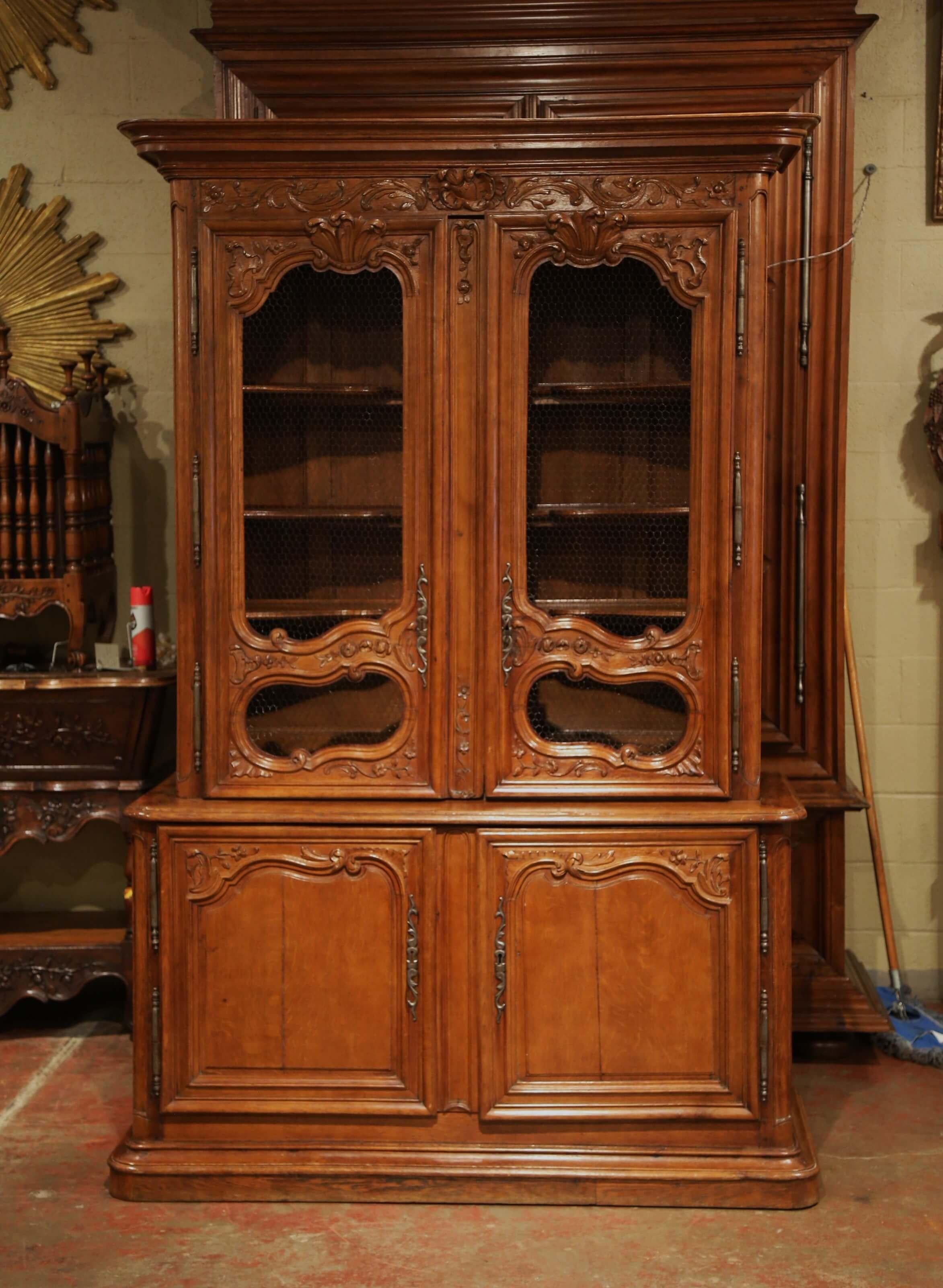 Display your fine Quimper or China collection in this museum quality antique display cabinet. Crafted in Normandy circa 1760, the exceptional buffet deux-corps is in immaculate condition. The cabinet features a flat molded cornice over foliage