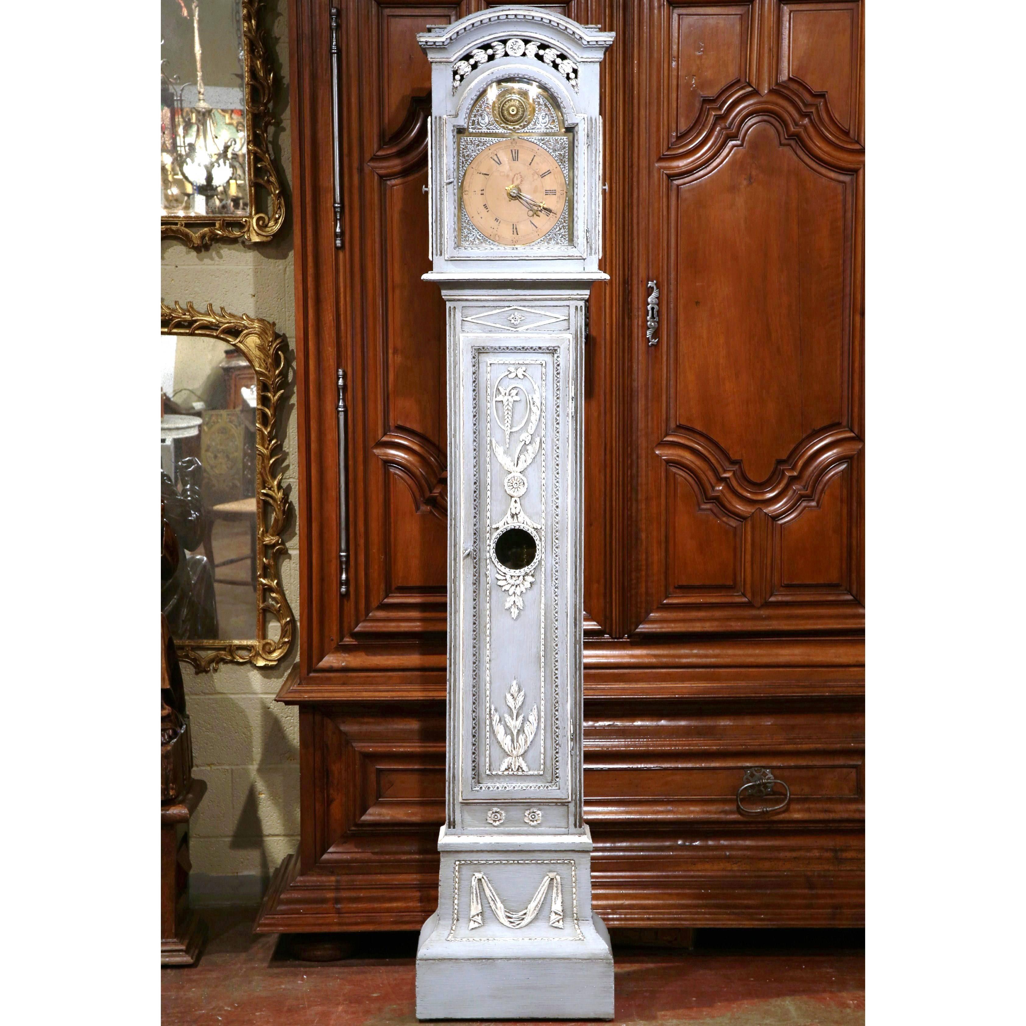Crafted in northern France, circa 1800, this elegant tall case clock features a carved and pierced bonnet top decorated with intricate carvings. The long front door features floral and leaf decor, and the bottom is embellished with swag motifs. The